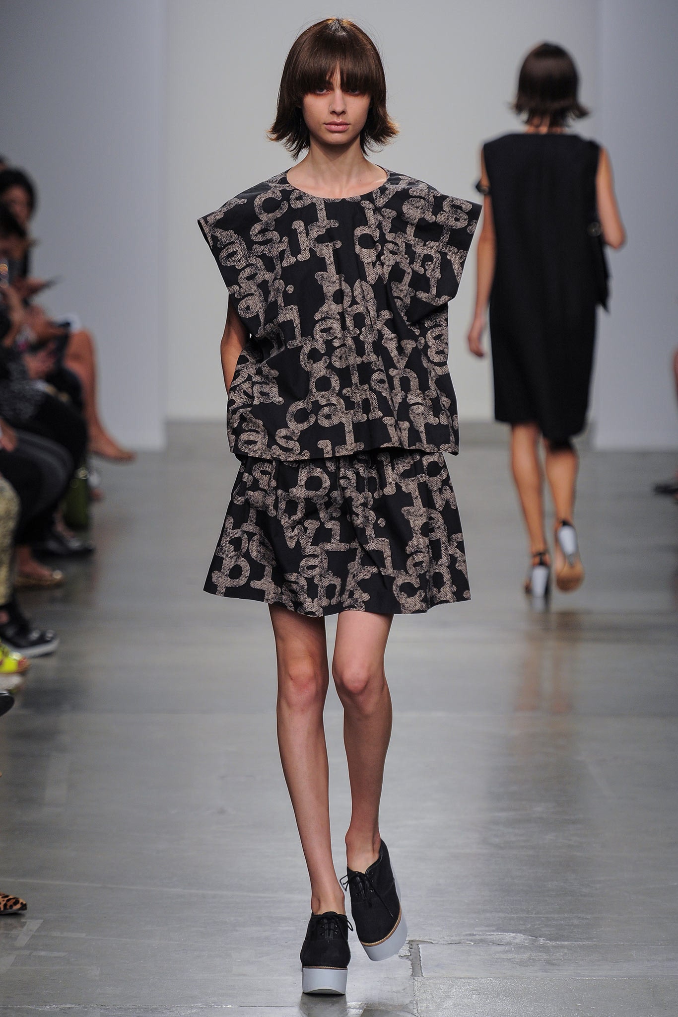 A relaxed black sleeveless dress with a high neckline and printed design.