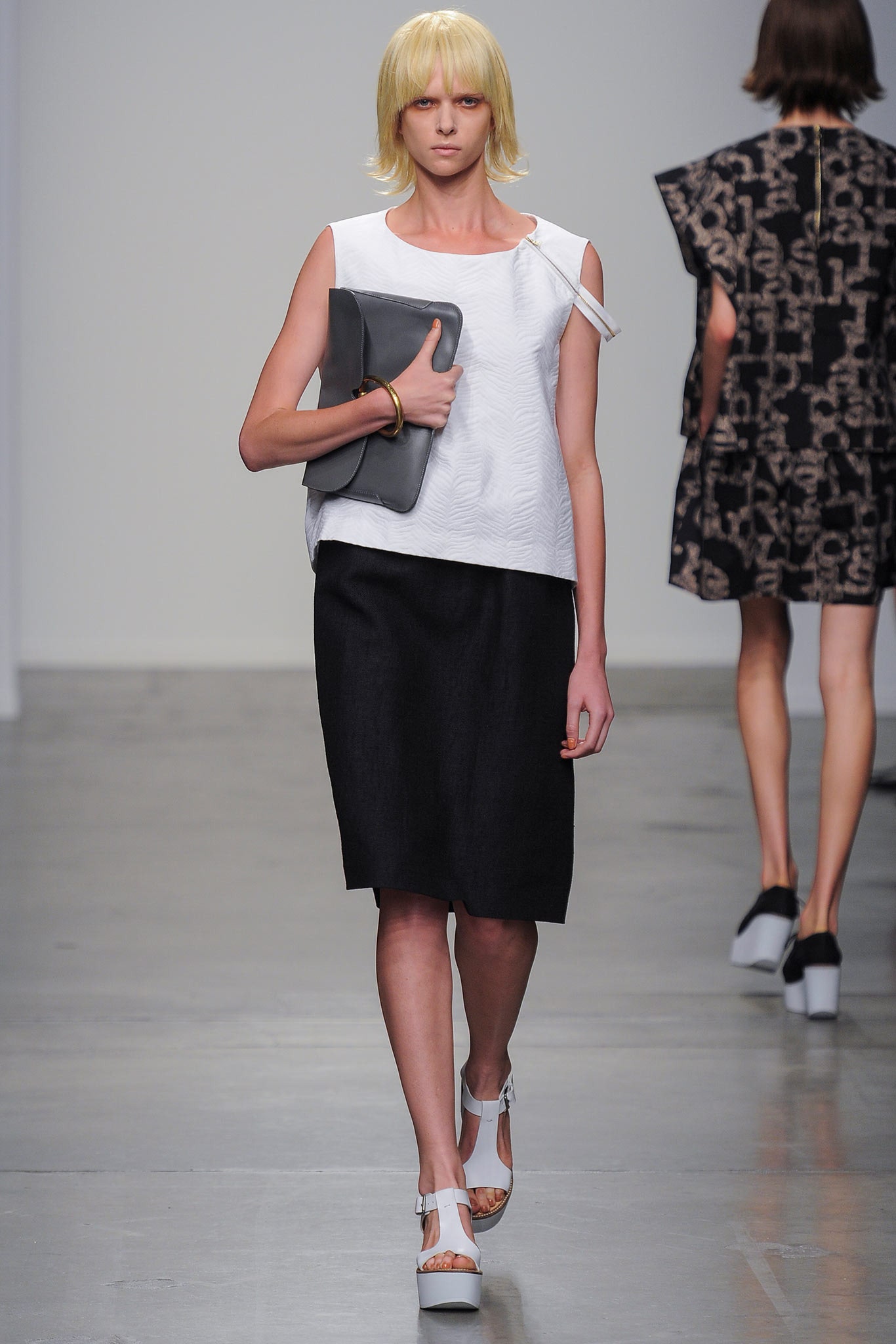 A fitted white sleeveless top paired with a black skirt featuring an asymmetric design.