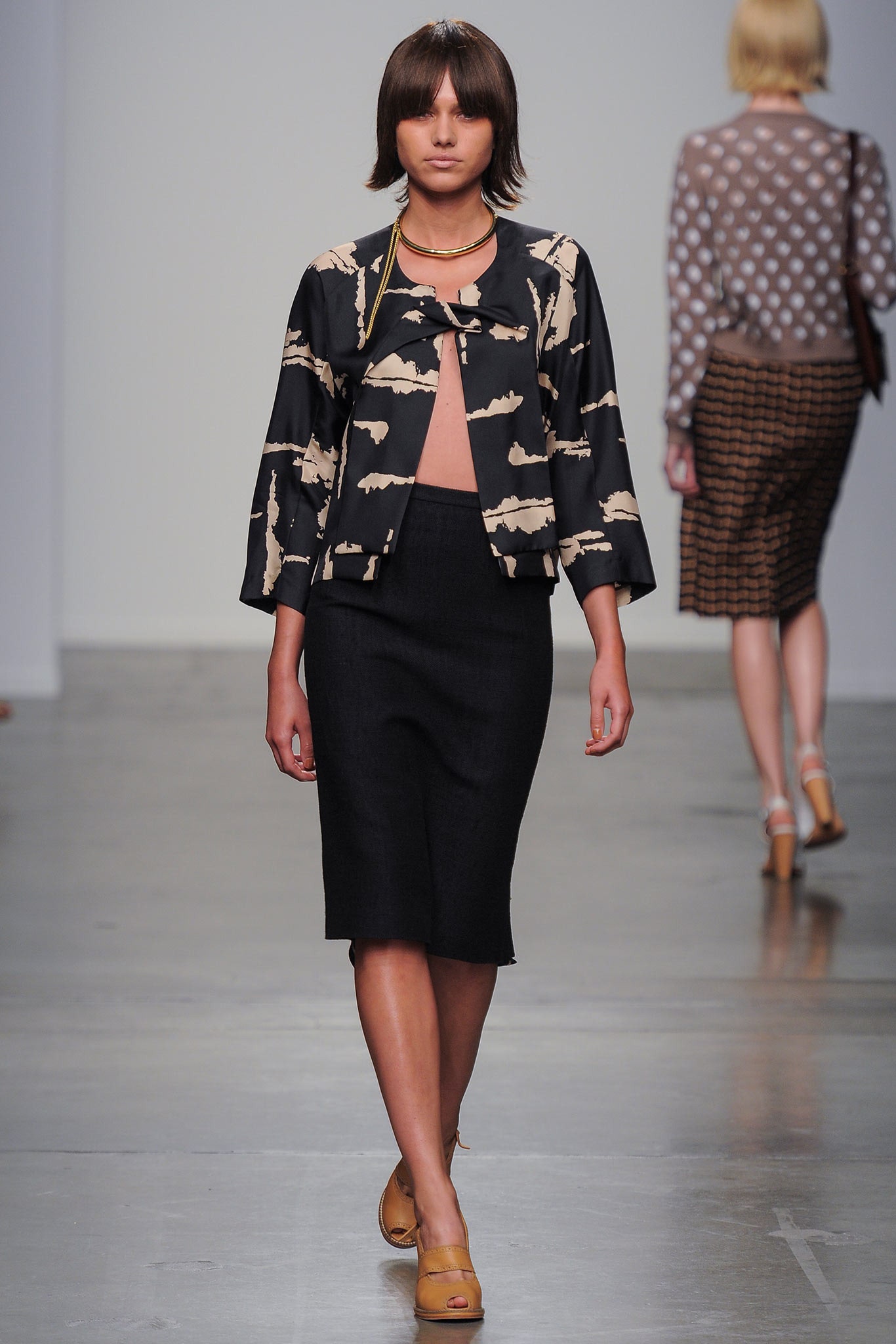 A fitted black printed jacket paired with a cream pencil skirt for a chic look.