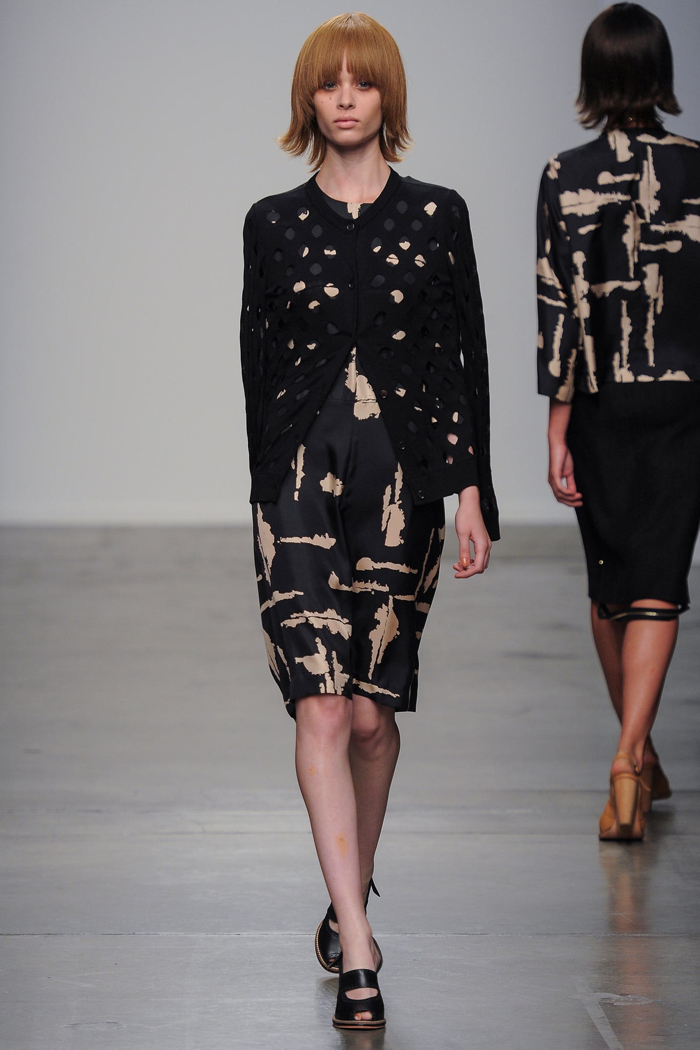 A fitted black dress with a printed design, complemented by a stylish black jacket.