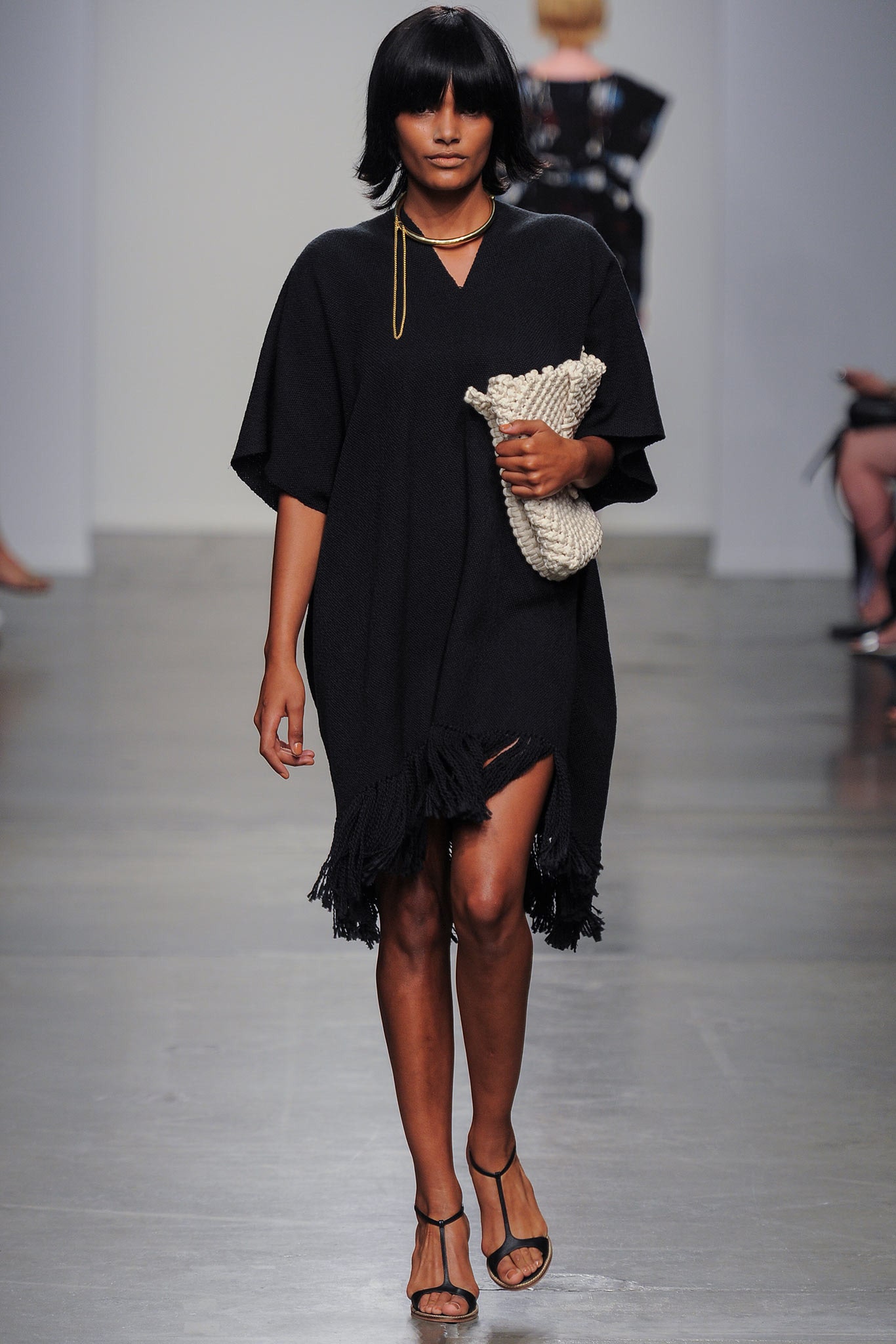 A relaxed black sleeveless dress with a V-neckline and fringed detailing.