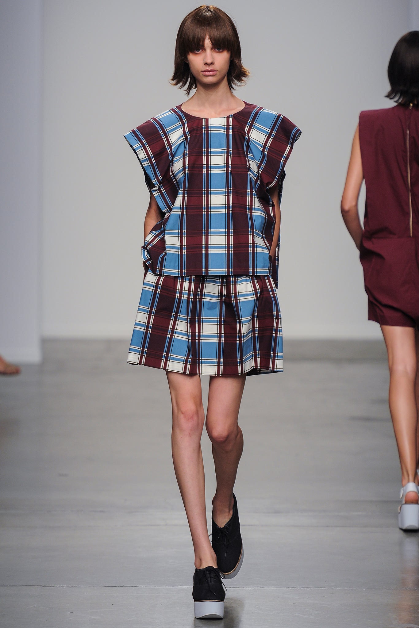 A relaxed blue and burgundy checked dress with a sleeveless design and pleated detail.