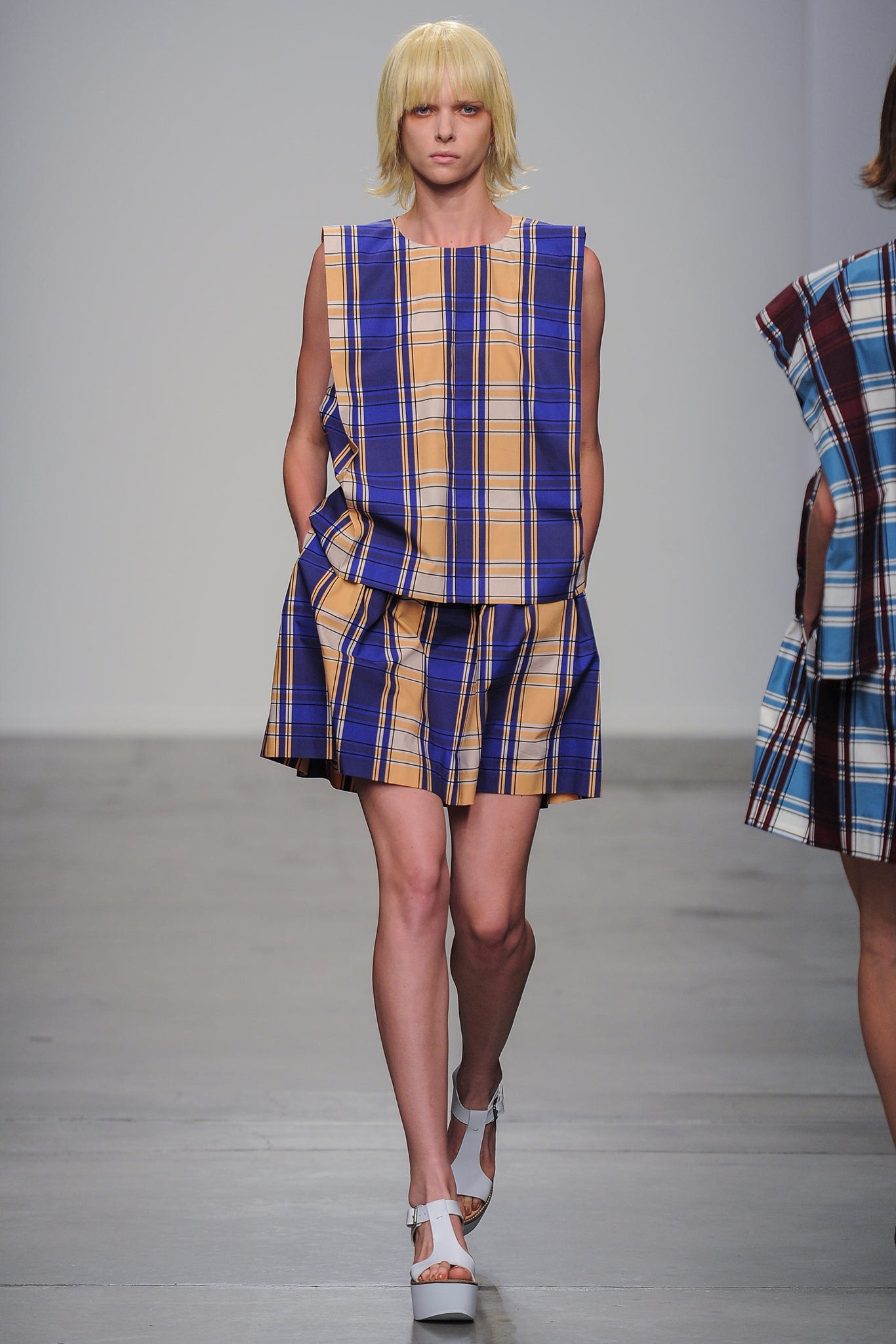 A relaxed sleeveless dress in blue and yellow check pattern with a collared design.