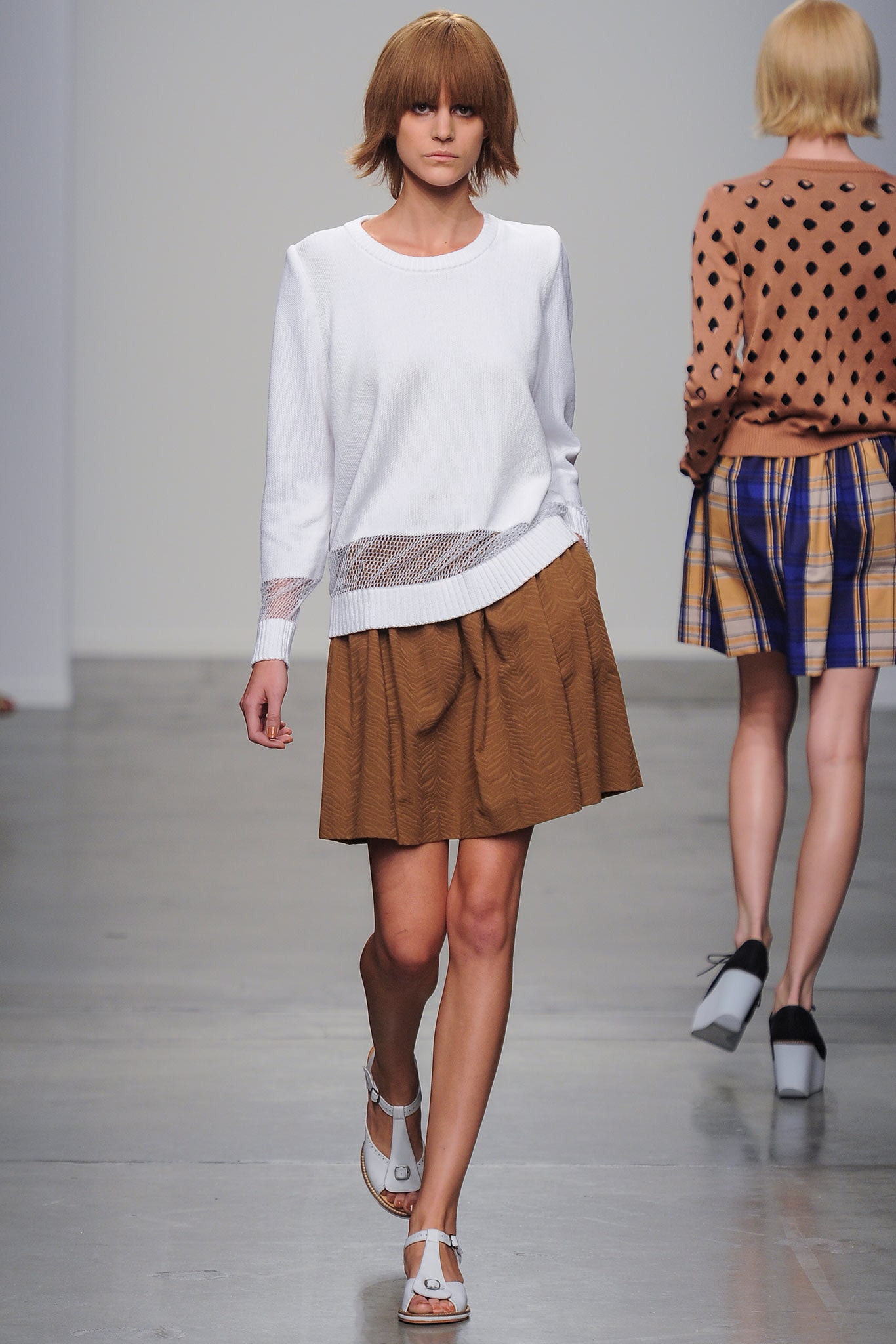 A relaxed white top paired with a pleated brown skirt, perfect for casual wear.