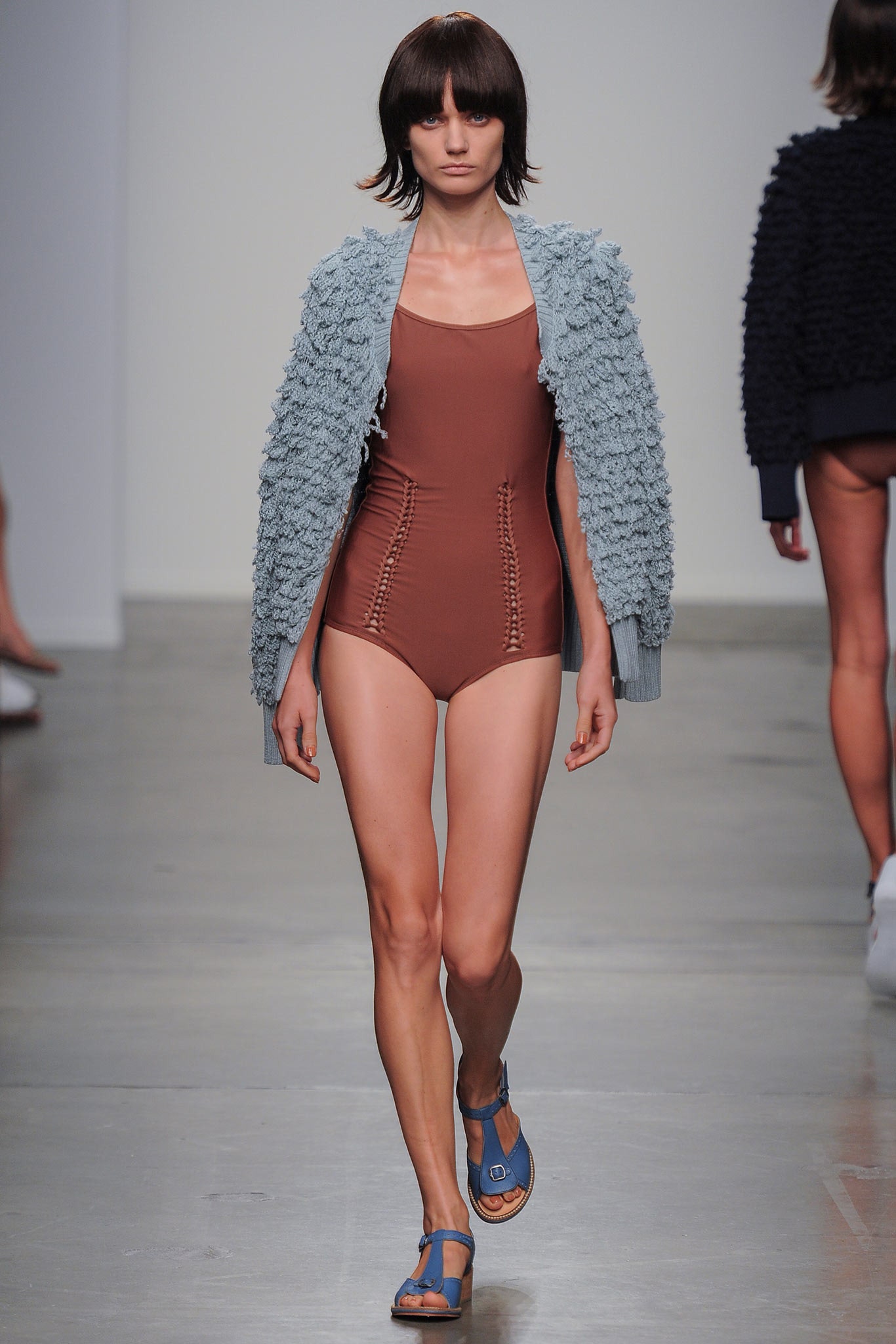 A fitted brown swimsuit paired with a layered blue cardigan for a stylish beach look.