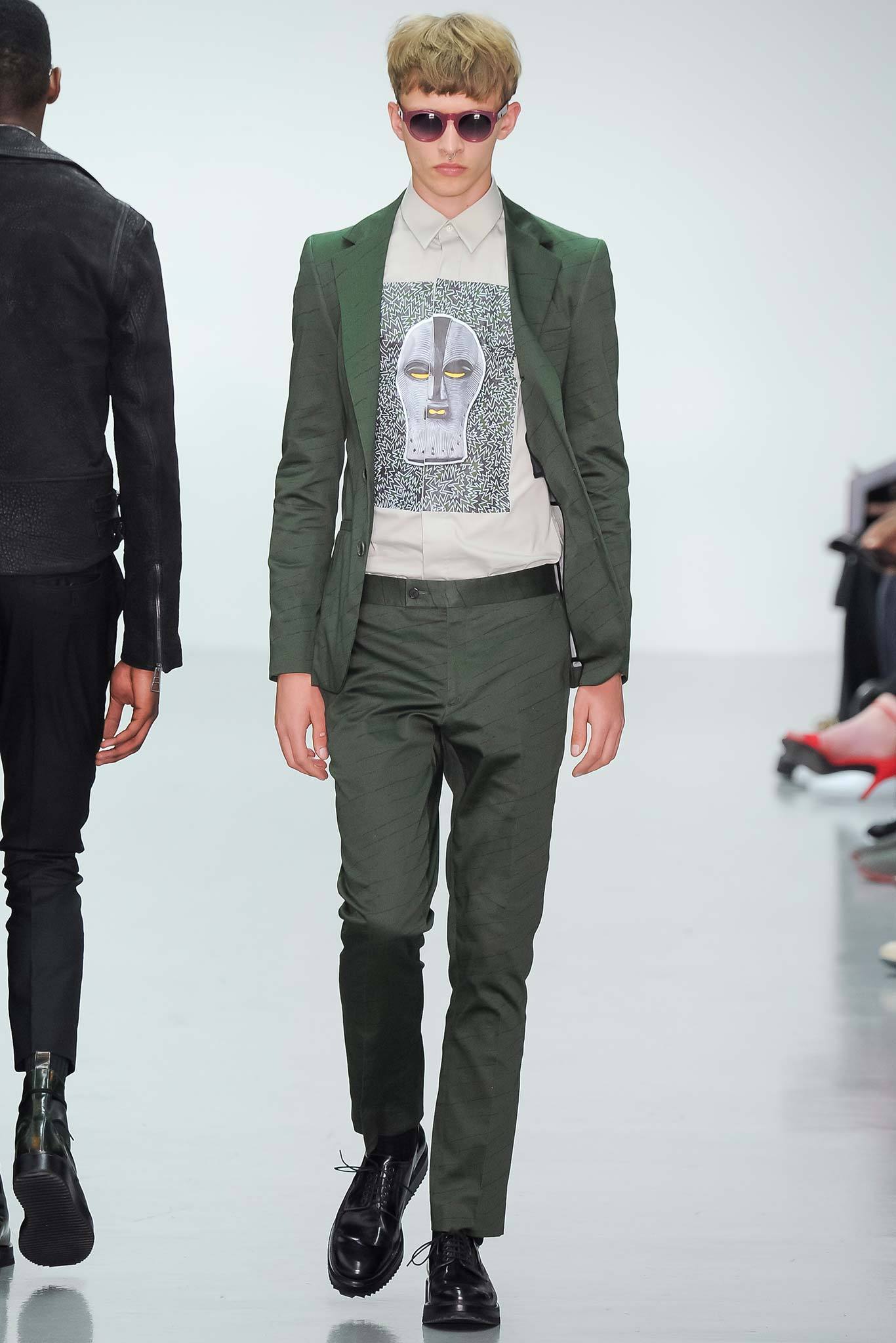 This tailored suit in a rich green hue features a structured silhouette that enhances its modern appeal. The long-sleeve collared shirt underneath adds a layer of sophistication, while the buttoned detail provides a polished finish.