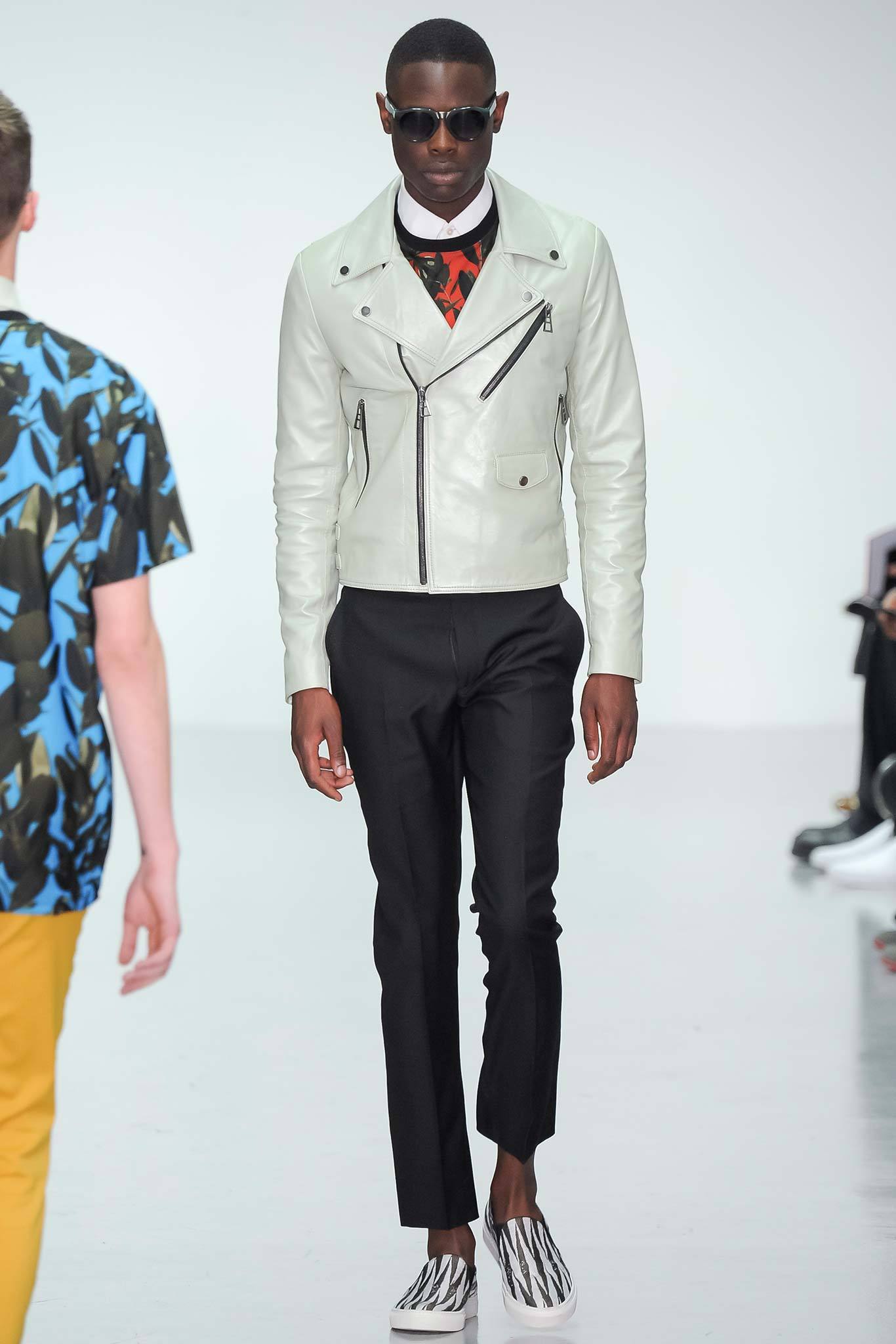 This fitted jacket in white leather features a striking zippered front and a structured silhouette that contrasts sharply with the sleek black pants. The combination creates a modern, streamlined look, emphasizing clean lines and a contemporary aesthetic.