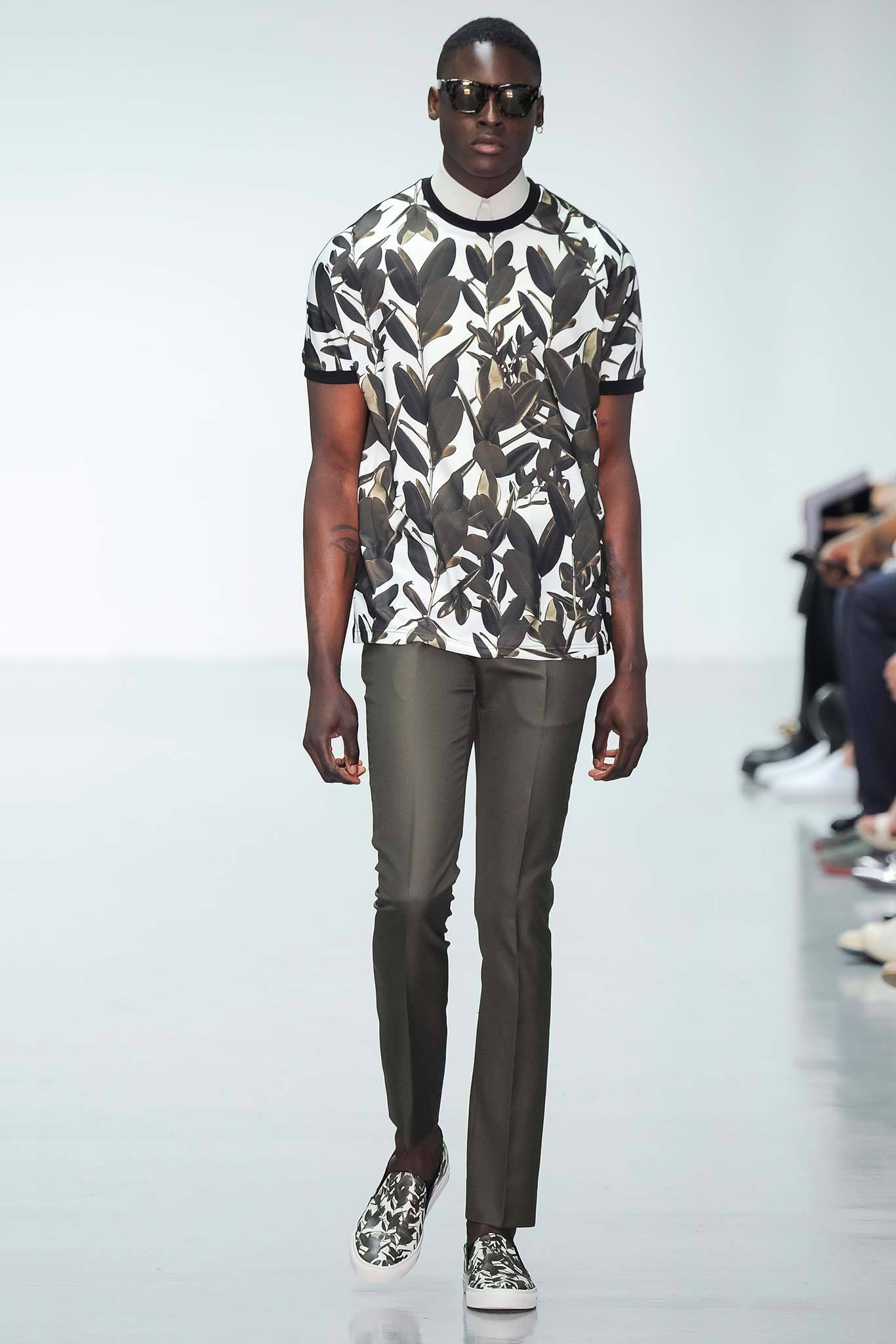 This outfit features a fitted short-sleeve shirt adorned with a bold leaf print, creating a striking visual impact. Paired with straight-leg pants, the ensemble balances casual elegance with contemporary flair, making it a versatile choice for various occasions.