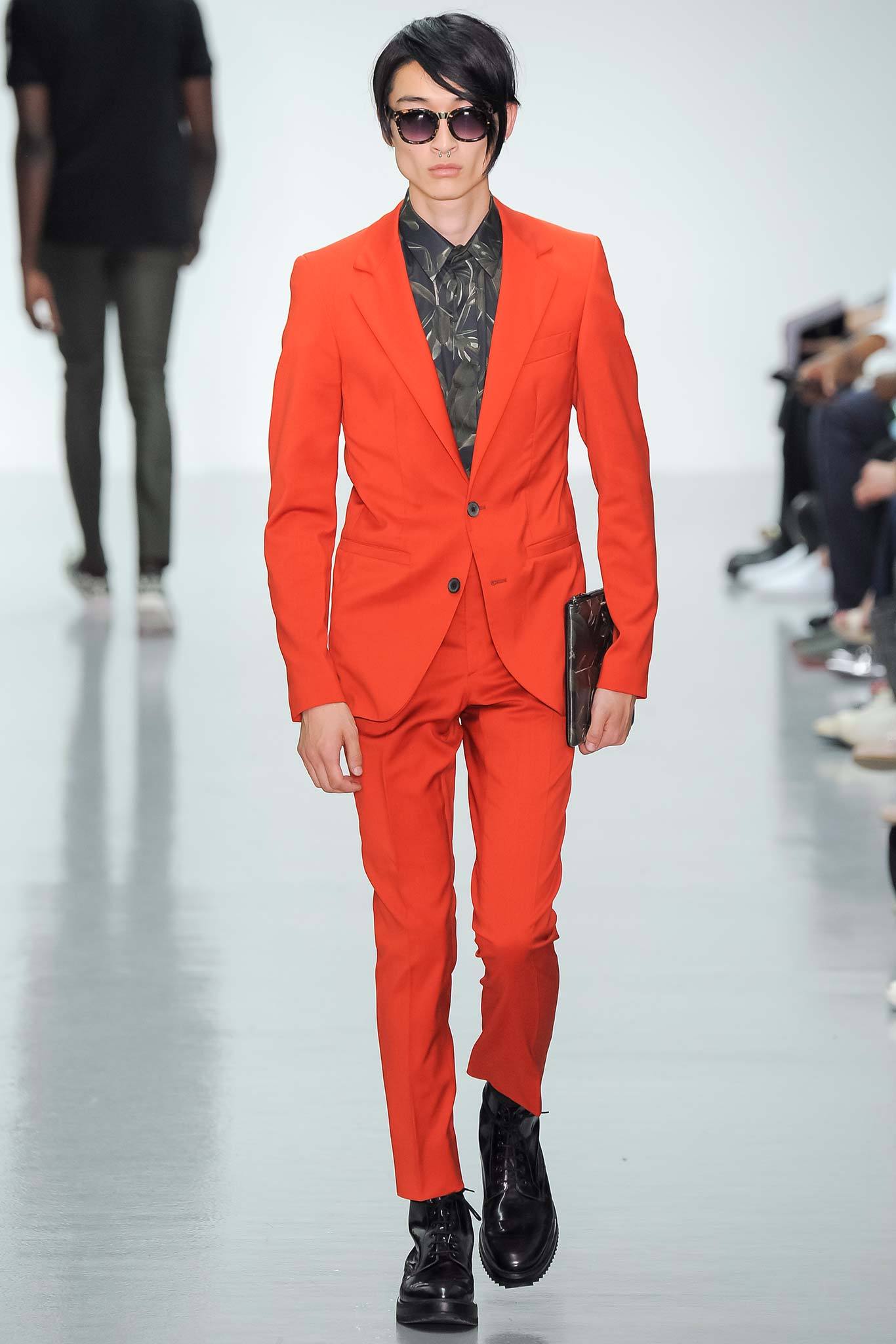 This tailored suit in a vibrant red hue commands attention with its sharp silhouette. The long-sleeve collared shirt beneath adds a layer of sophistication, while the buttoned details enhance its structured appeal.