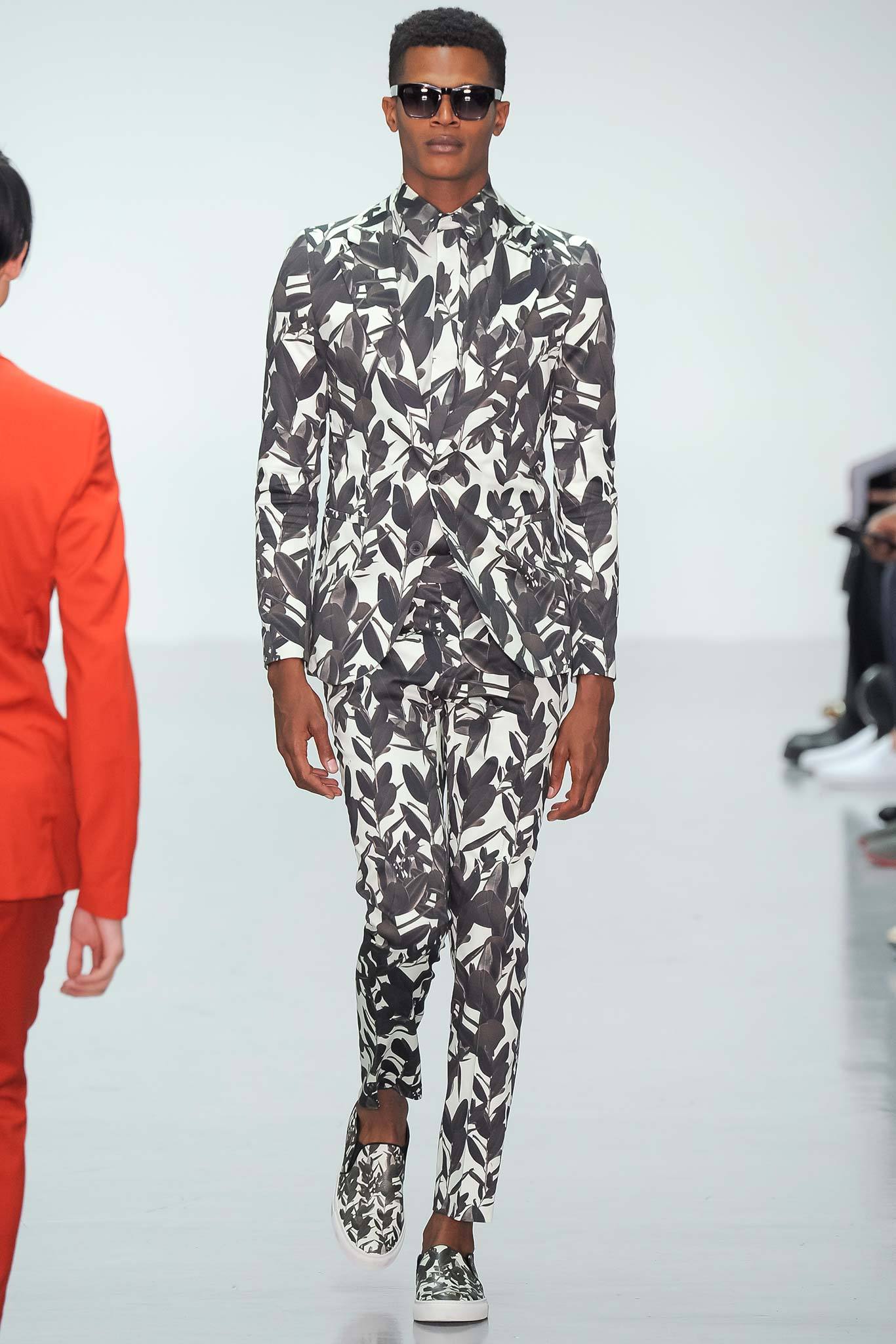 This fitted suit showcases a striking black and white leaf print, creating a bold visual impact. The long-sleeve collared jacket complements the tailored trousers, enhancing the overall silhouette with a contemporary flair.