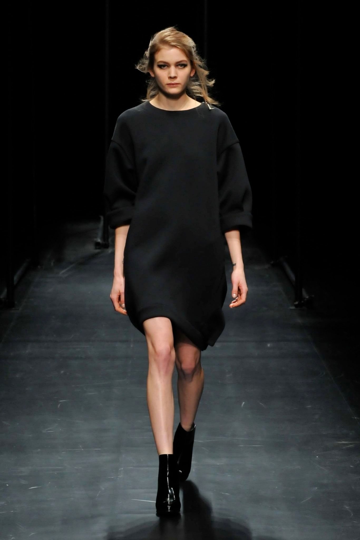 A relaxed black dress with long sleeves and an asymmetric design.