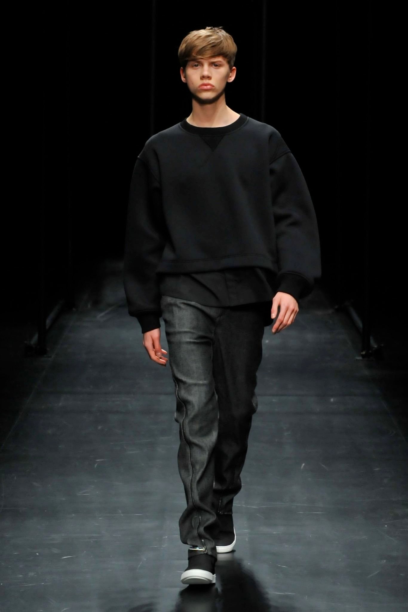 A relaxed black long-sleeve sweater paired with straight-leg gray pants.