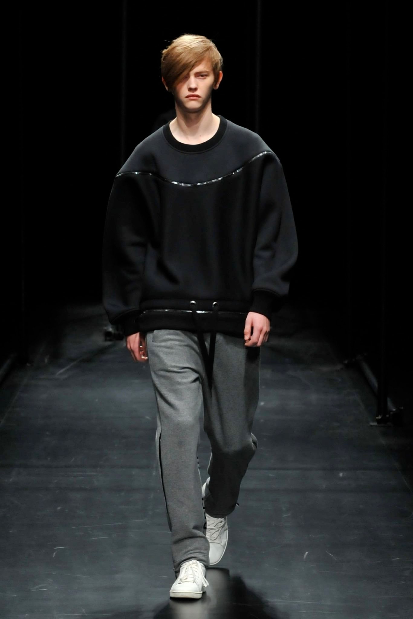 A relaxed black long-sleeve sweater paired with gray pants, featuring a zippered detail.