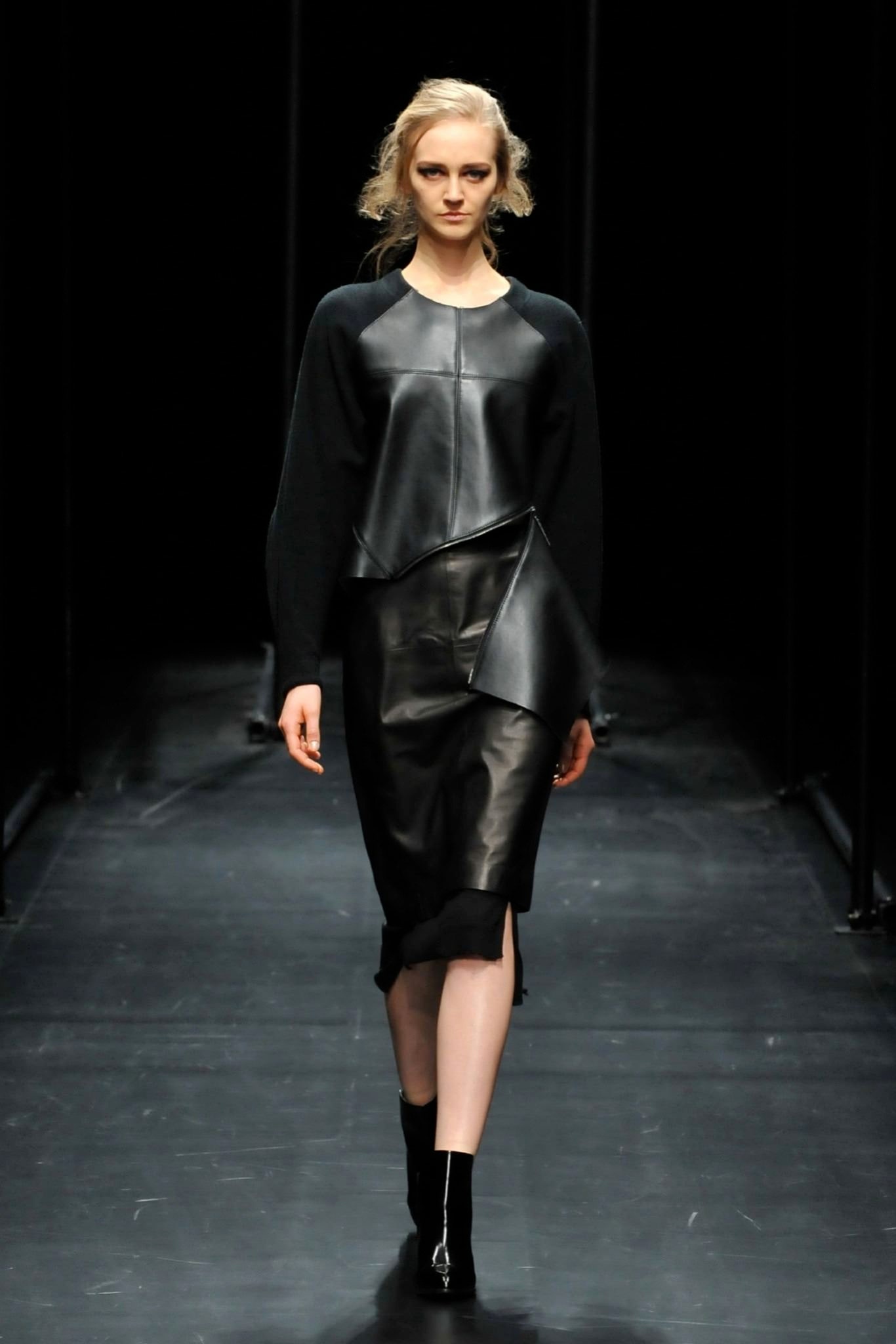 A fitted black leather dress with a sleeveless design and asymmetric details.