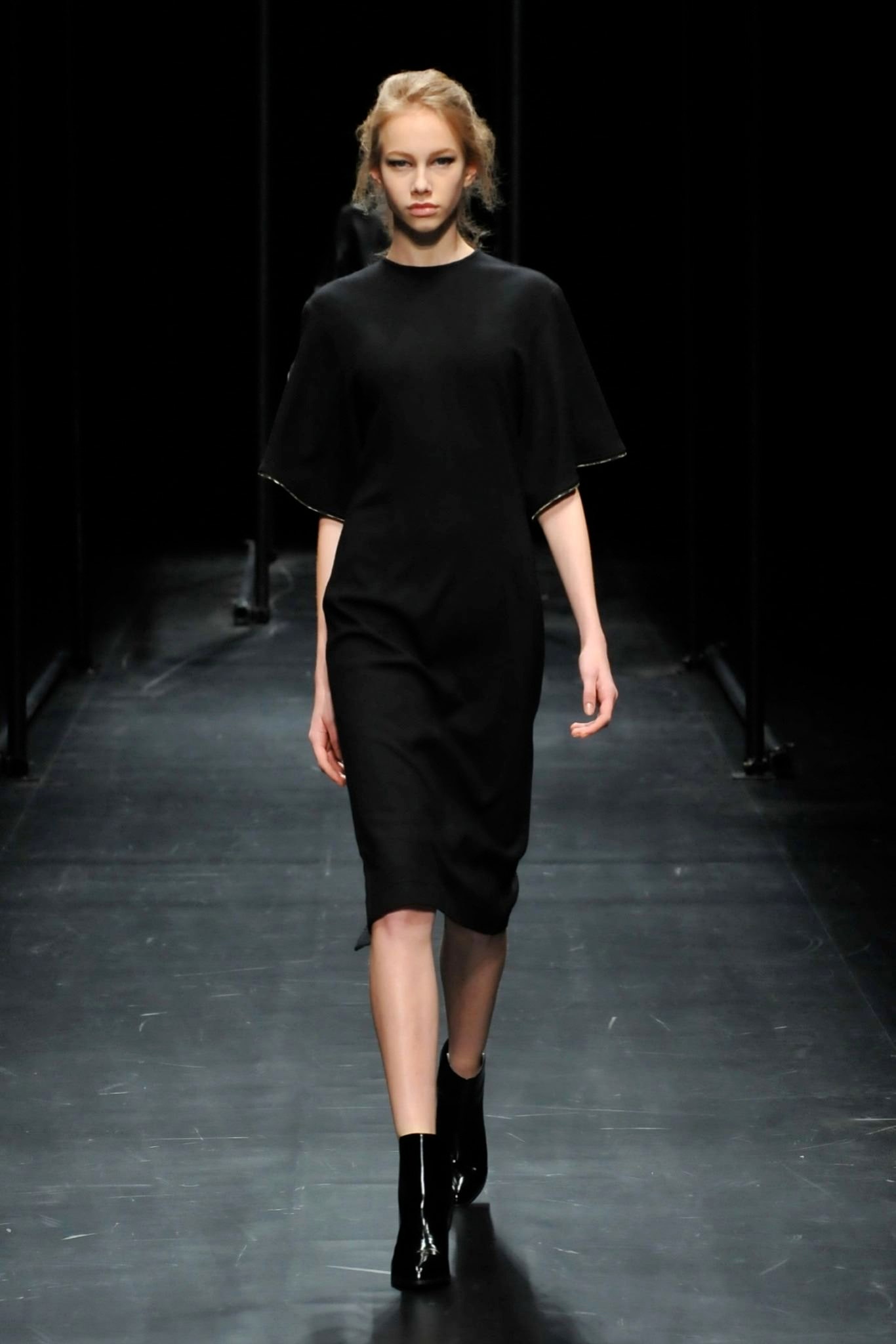 A fitted black dress with short sleeves and a straight silhouette.