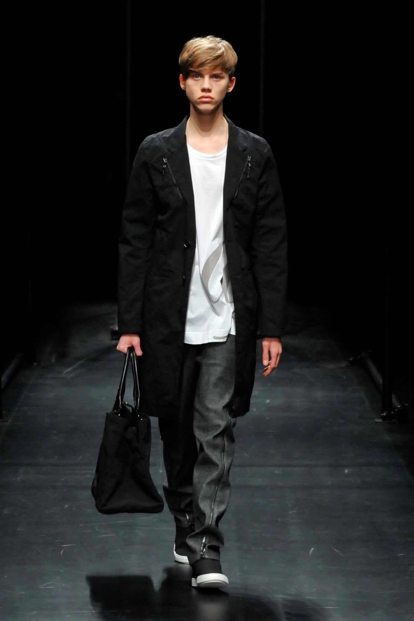 A relaxed black coat layered over a white collared shirt with buttoned details.