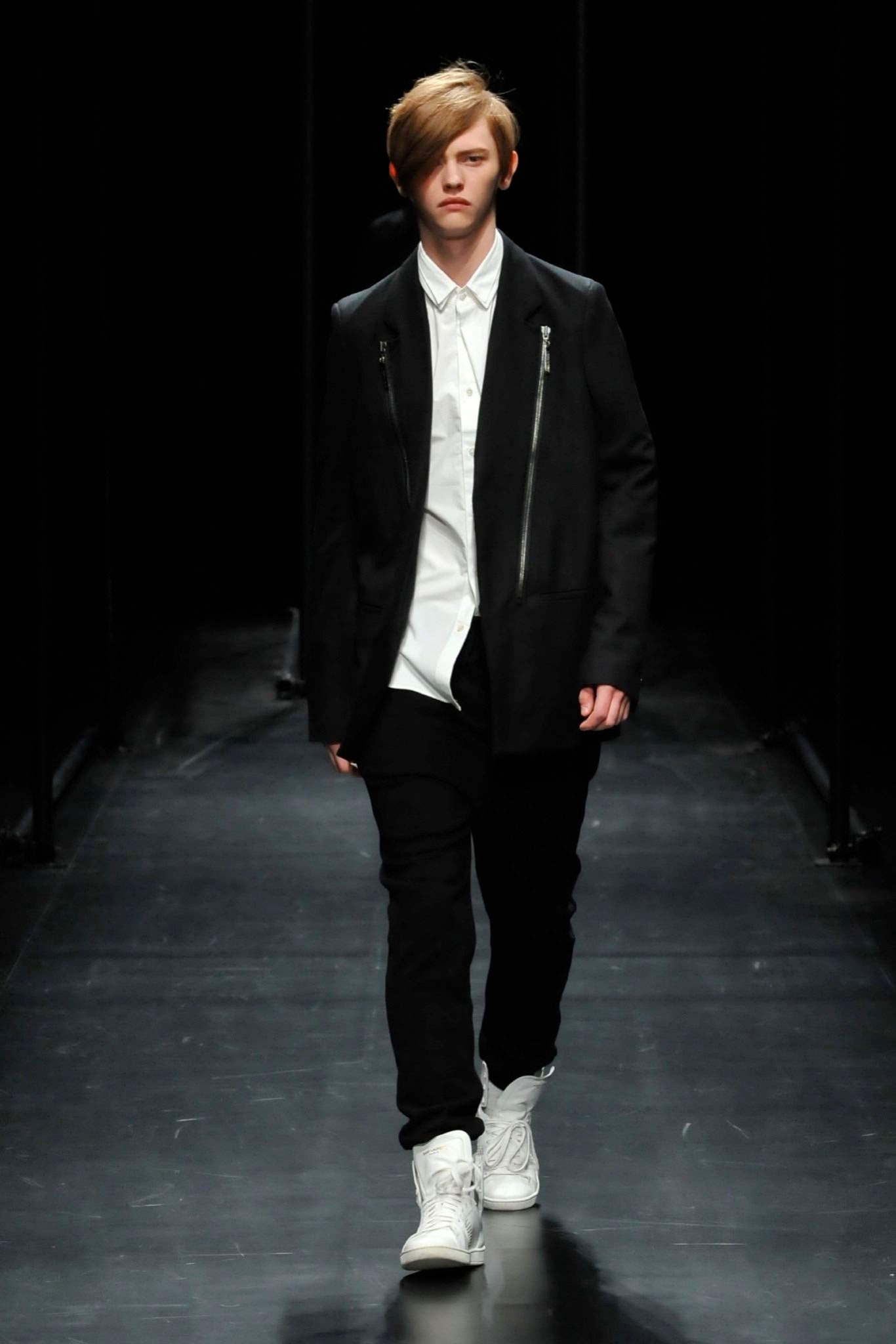 A fitted black jacket over a white collared shirt paired with black pants.