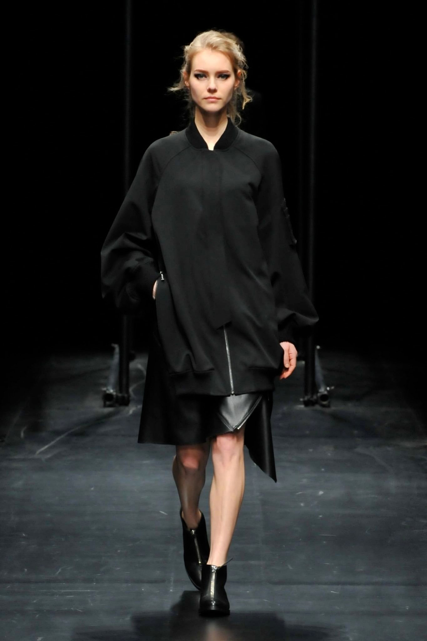 A relaxed black jacket dress with long sleeves and an asymmetric design.