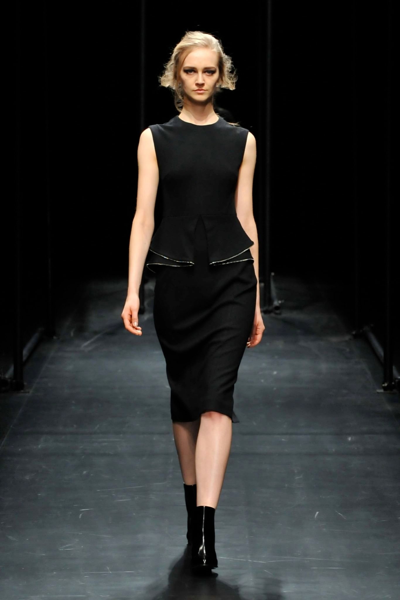 A fitted black sleeveless dress with a V-neckline and pencil silhouette.