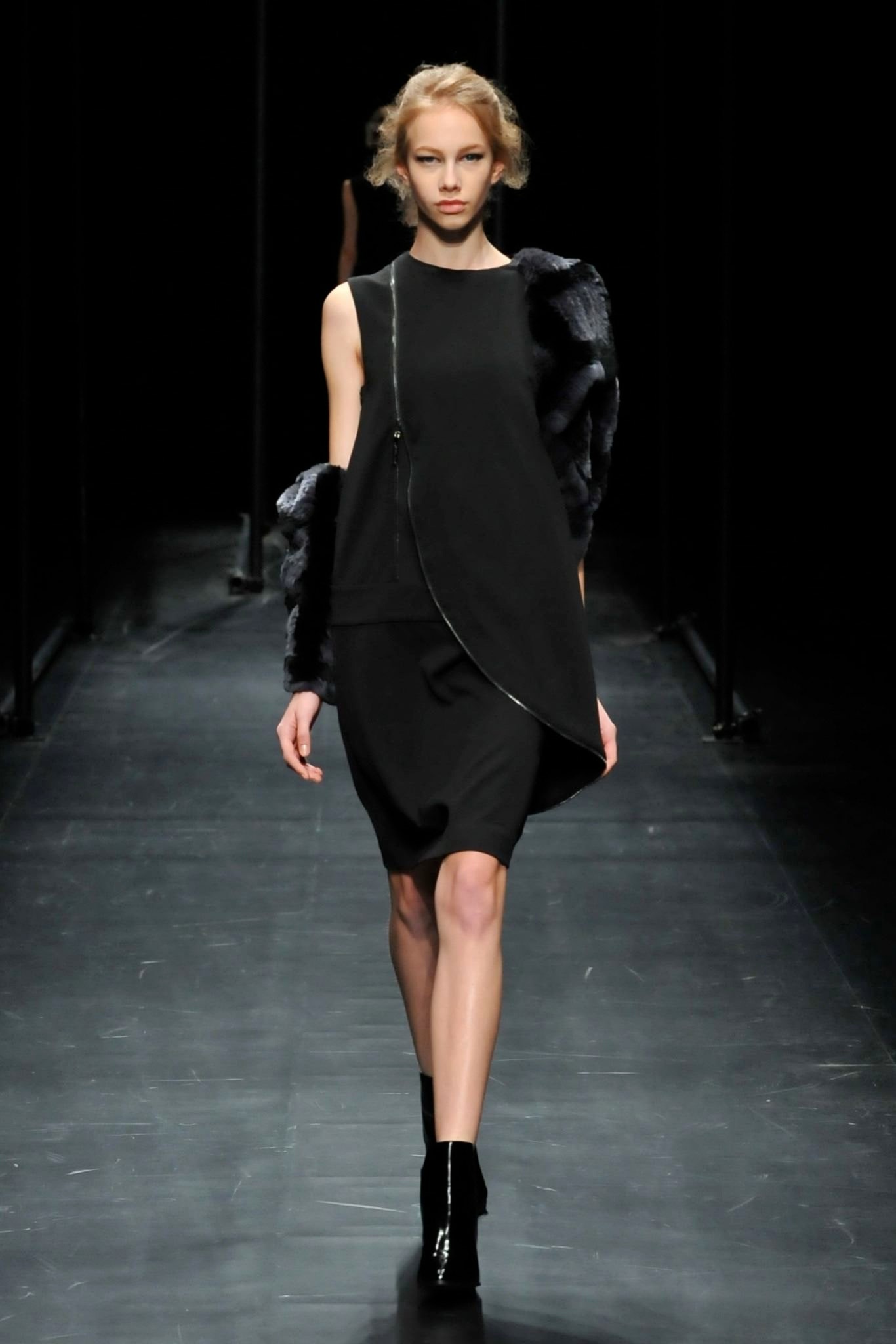 A fitted black sleeveless dress with an asymmetric design and layered detail.