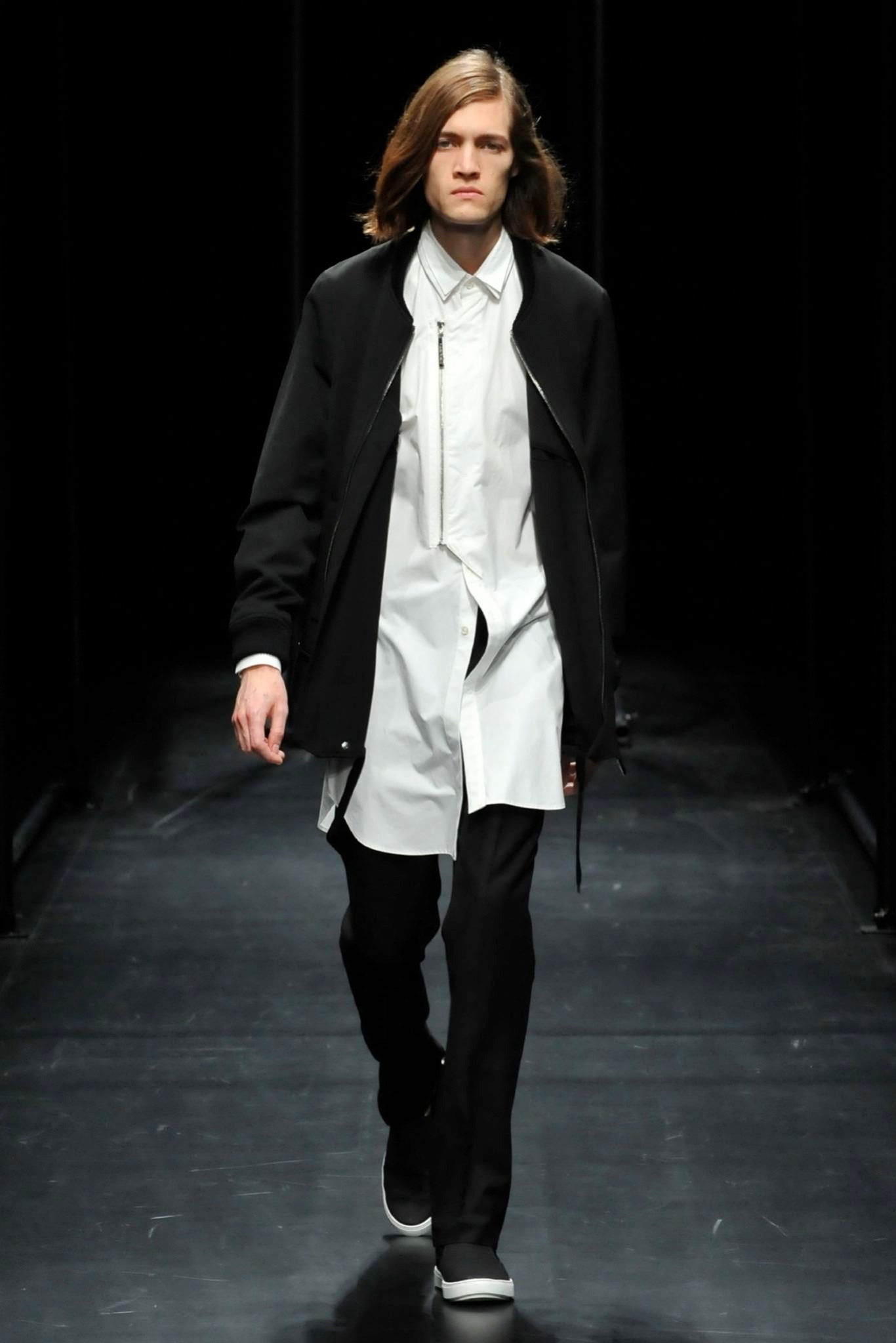 A relaxed black jacket layered over a collared white shirt with long sleeves.