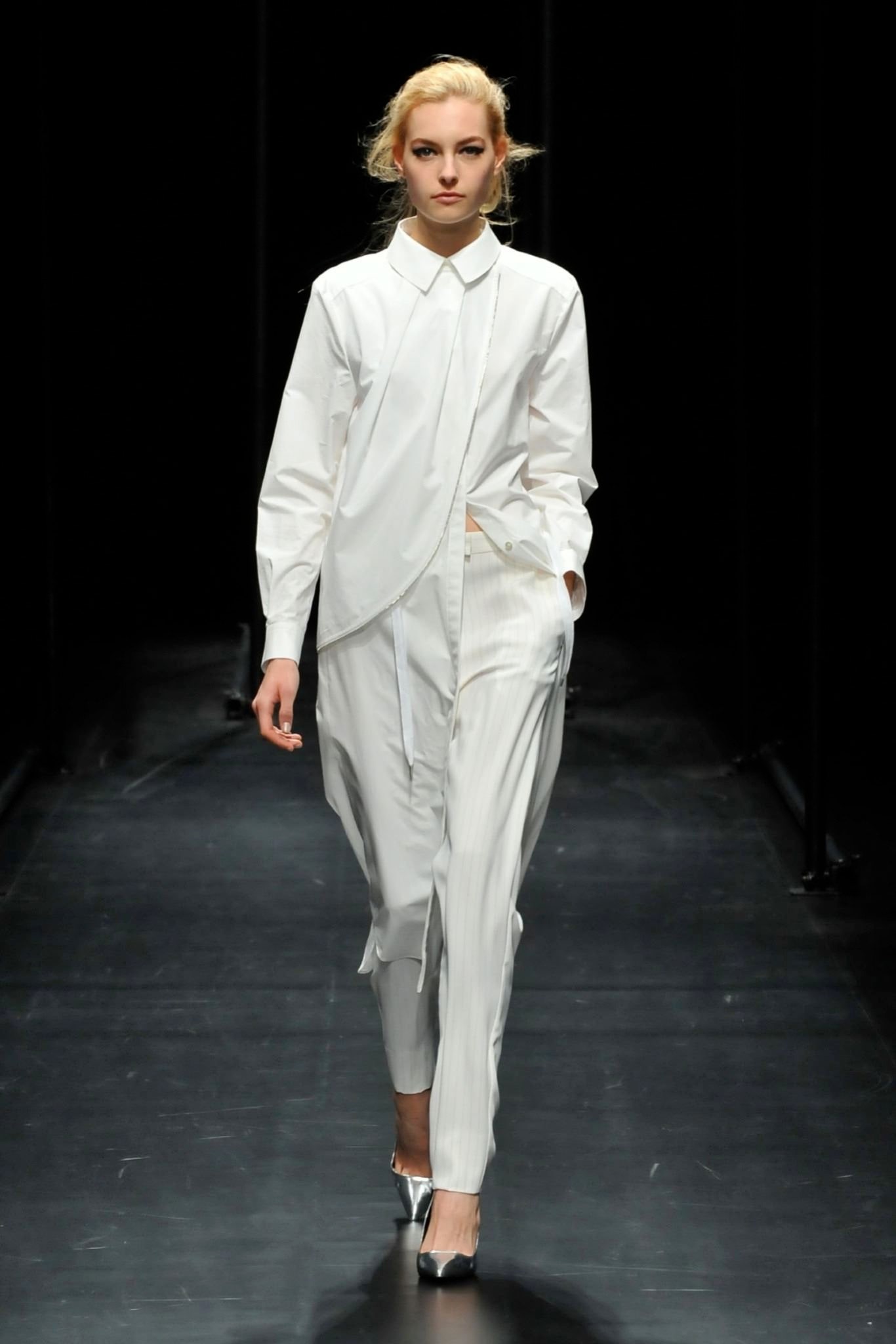 A relaxed white long-sleeve collared shirt paired with pleated pants featuring an asymmetric design.