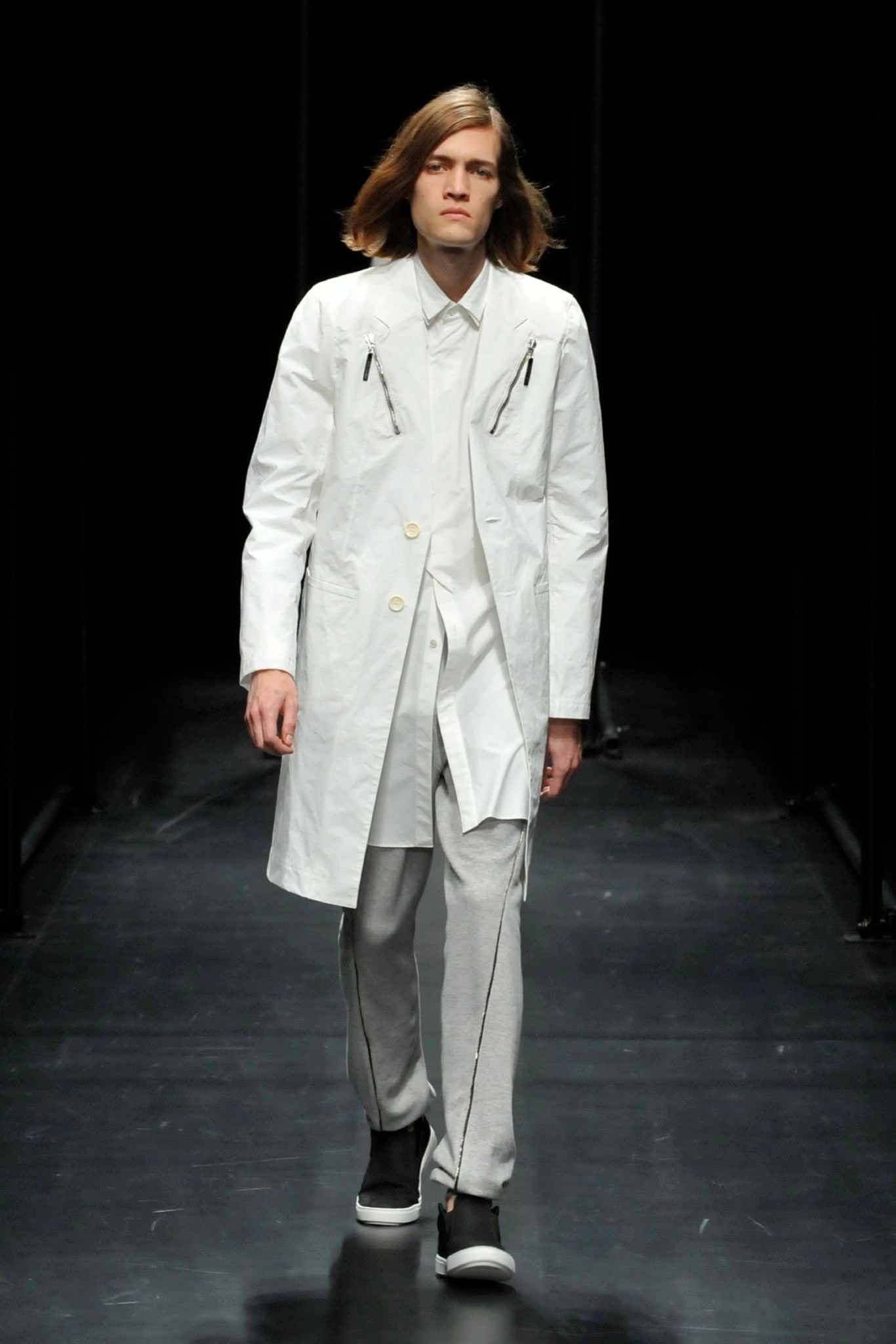 A relaxed white coat paired with gray pants featuring a collared design and zippered details.