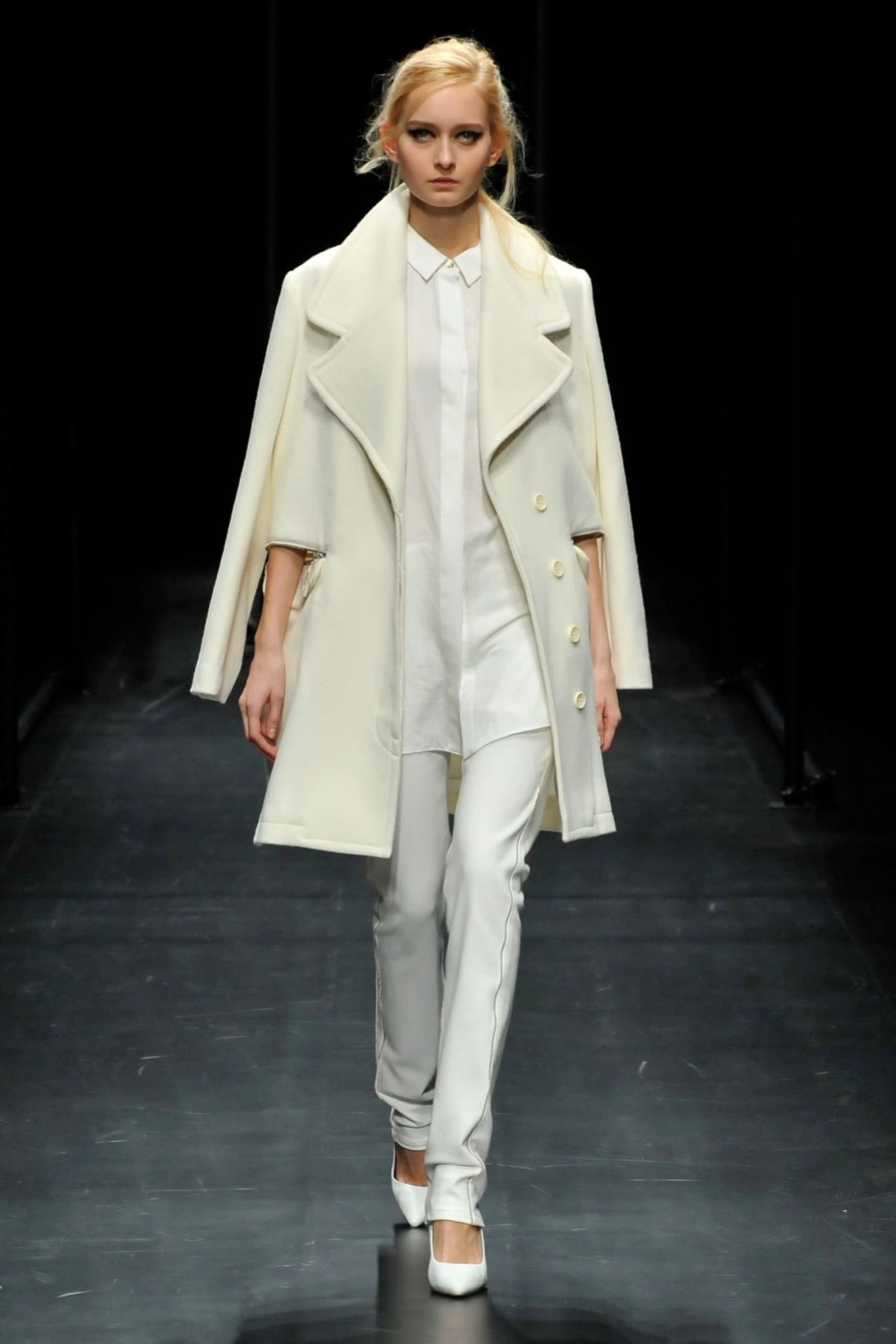 A fitted white wool coat with a collared neckline paired with tailored pants.