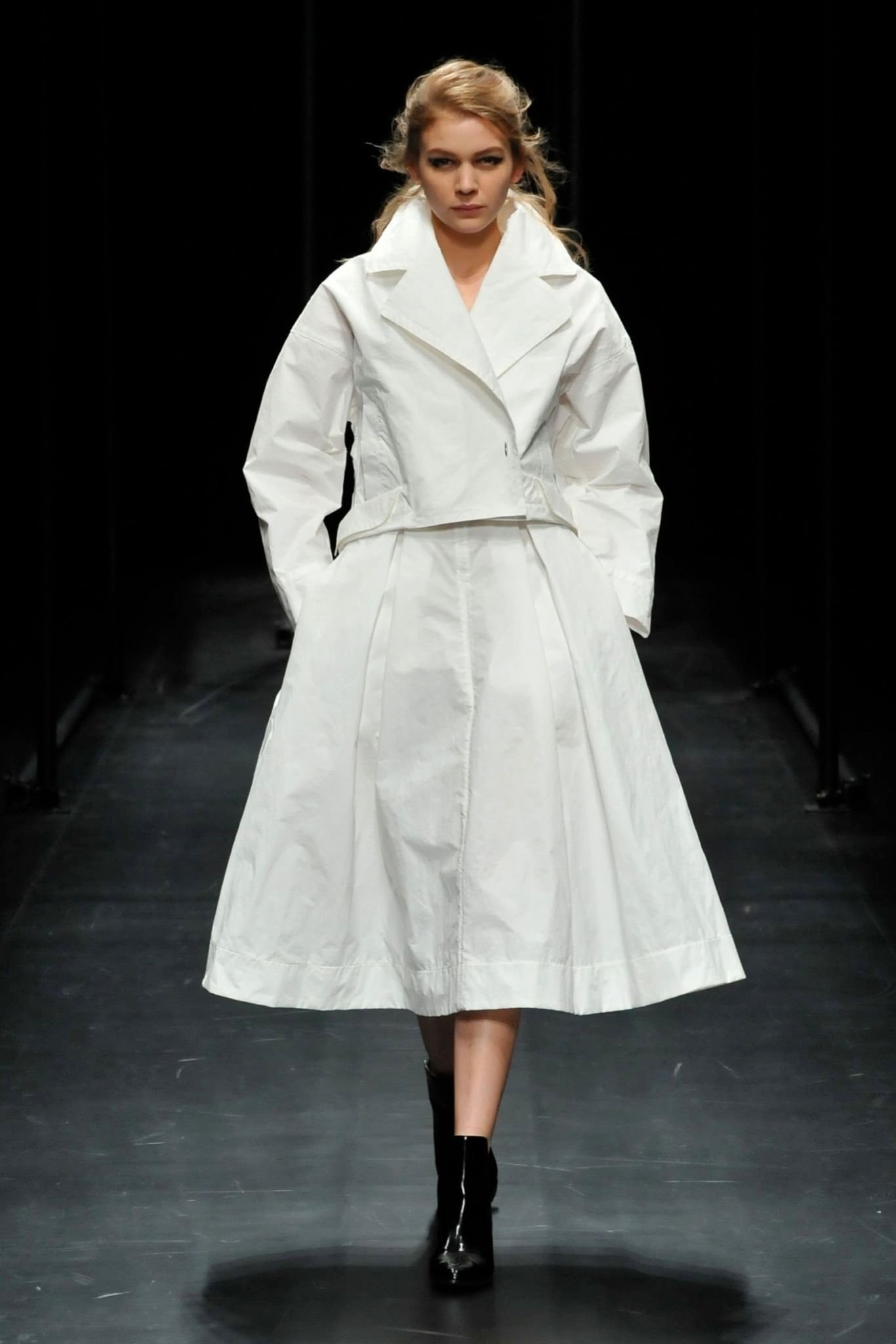 A fitted white cotton dress with a layered asymmetric design and long sleeves.
