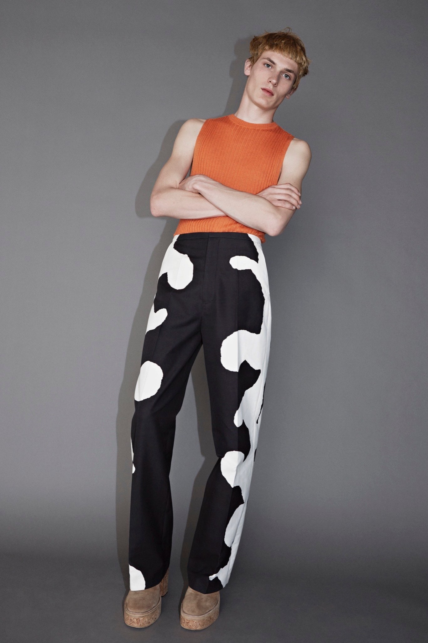 orange fitted sleeveless top and black white pants