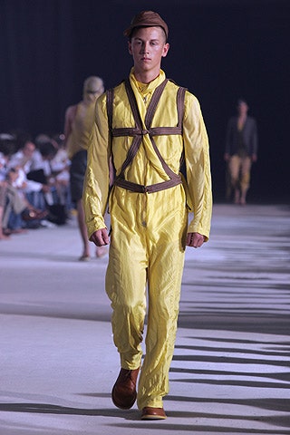 yellow fitted jumpsuit with brown hat
