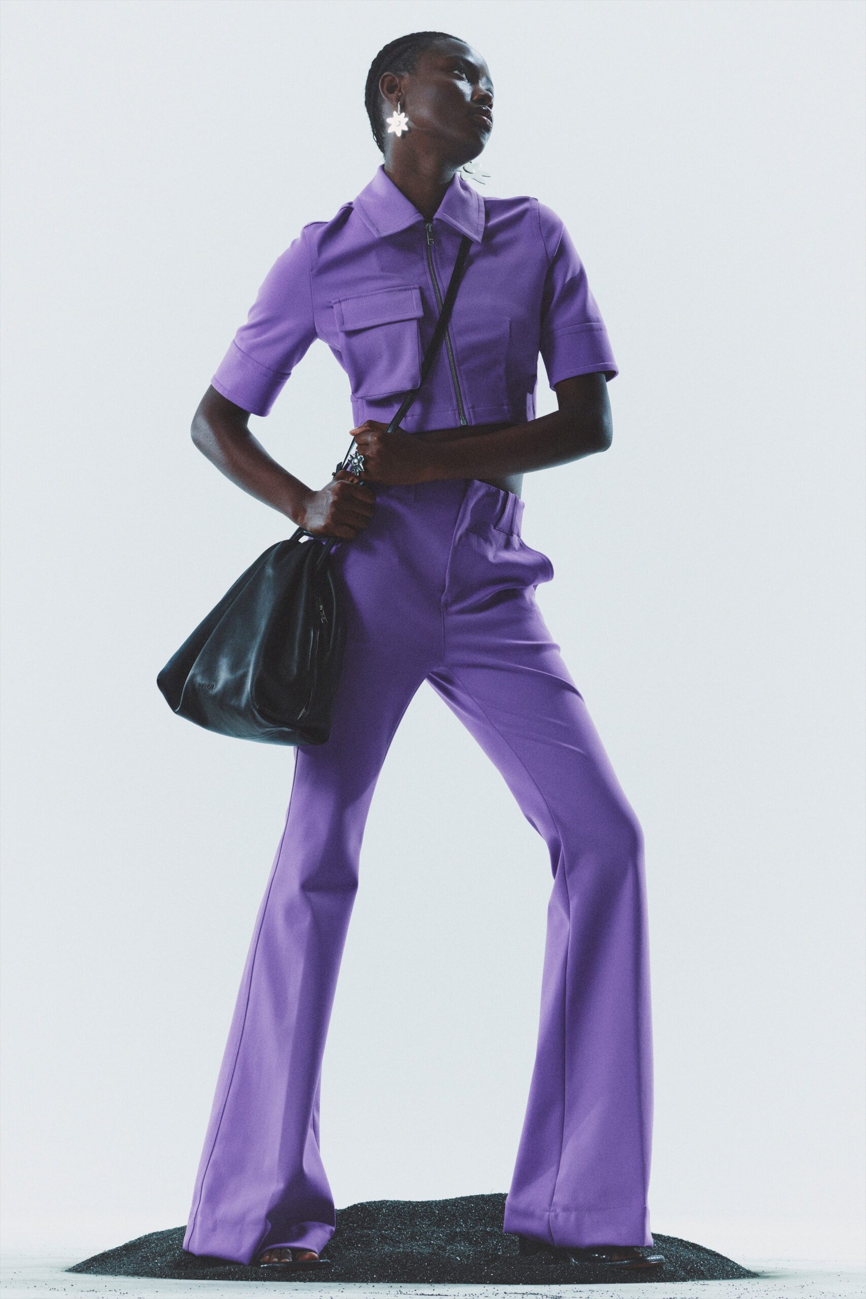 purple fitted jumpsuit with black bag