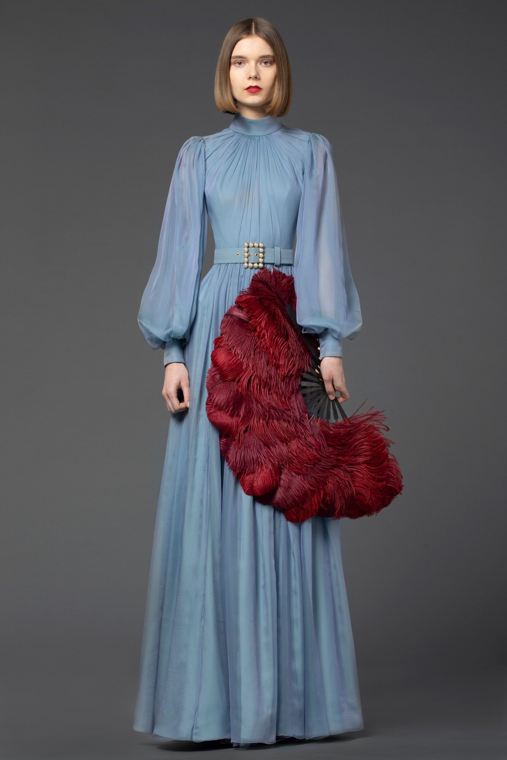 blue silk pleated gown with red feather accessory