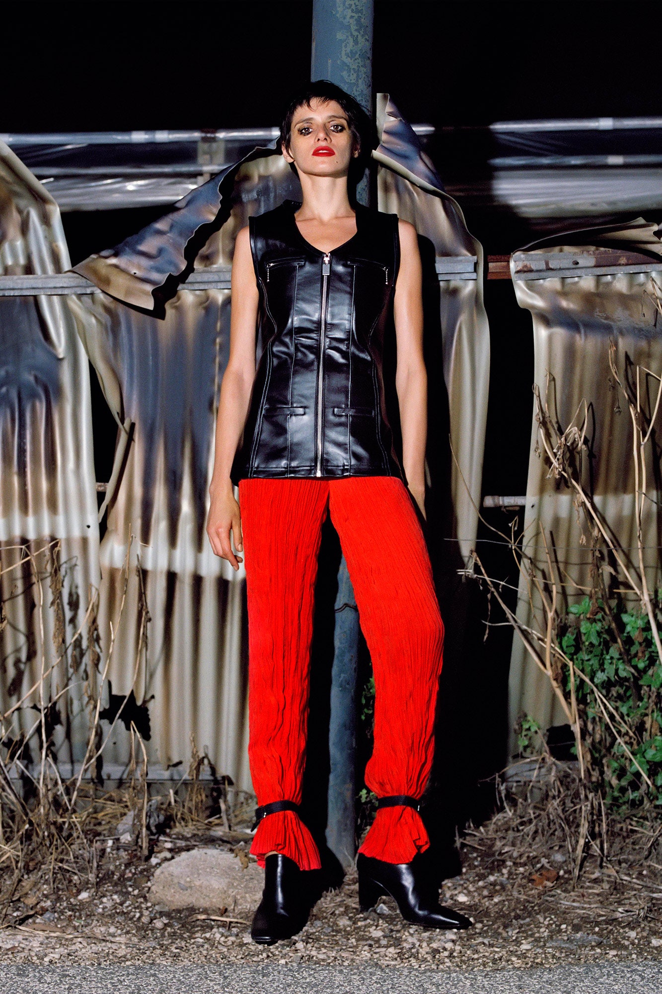 black leather sleeveless top and red pleated pants