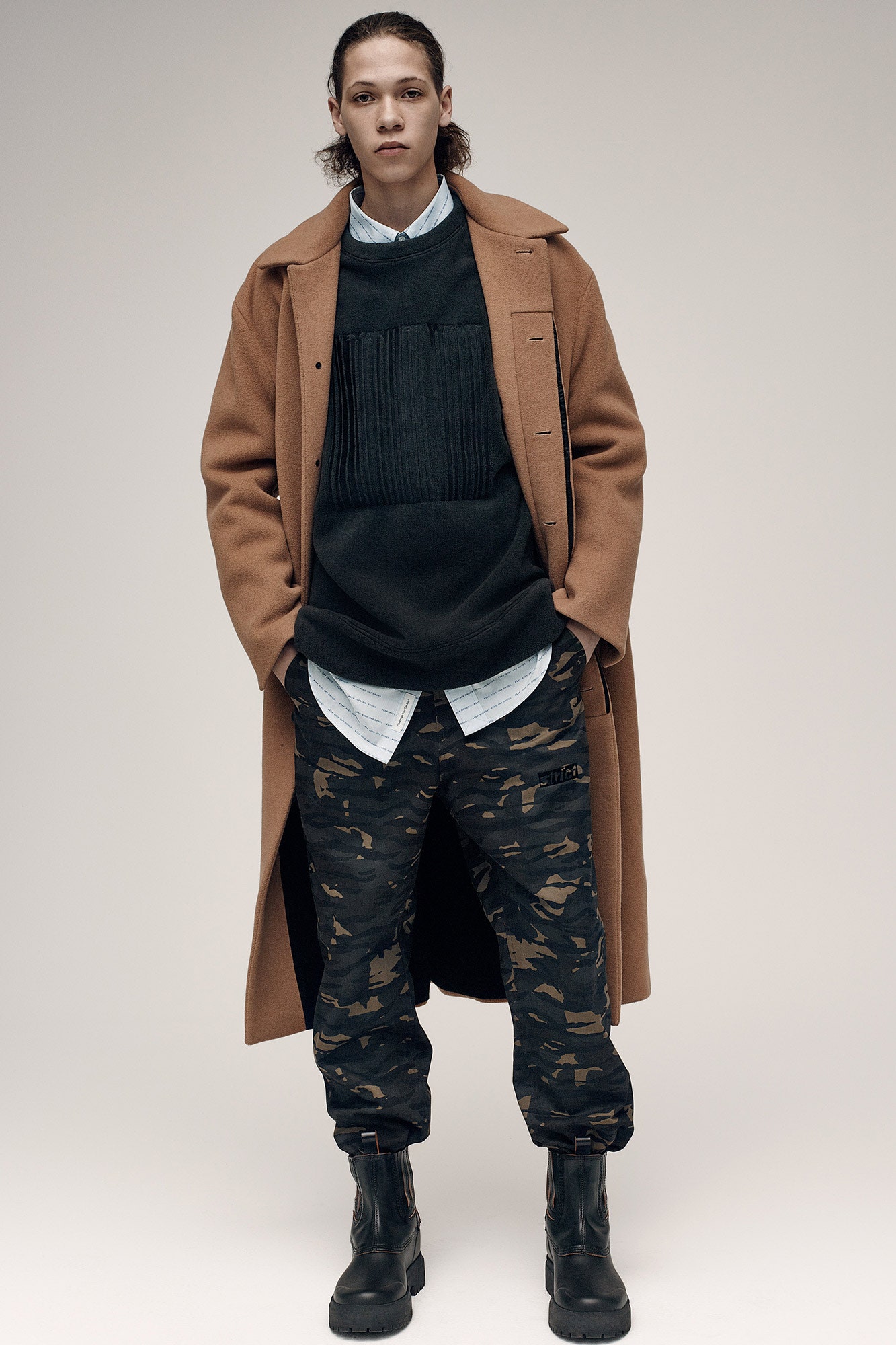 brown wool coat black sweater camouflage pants