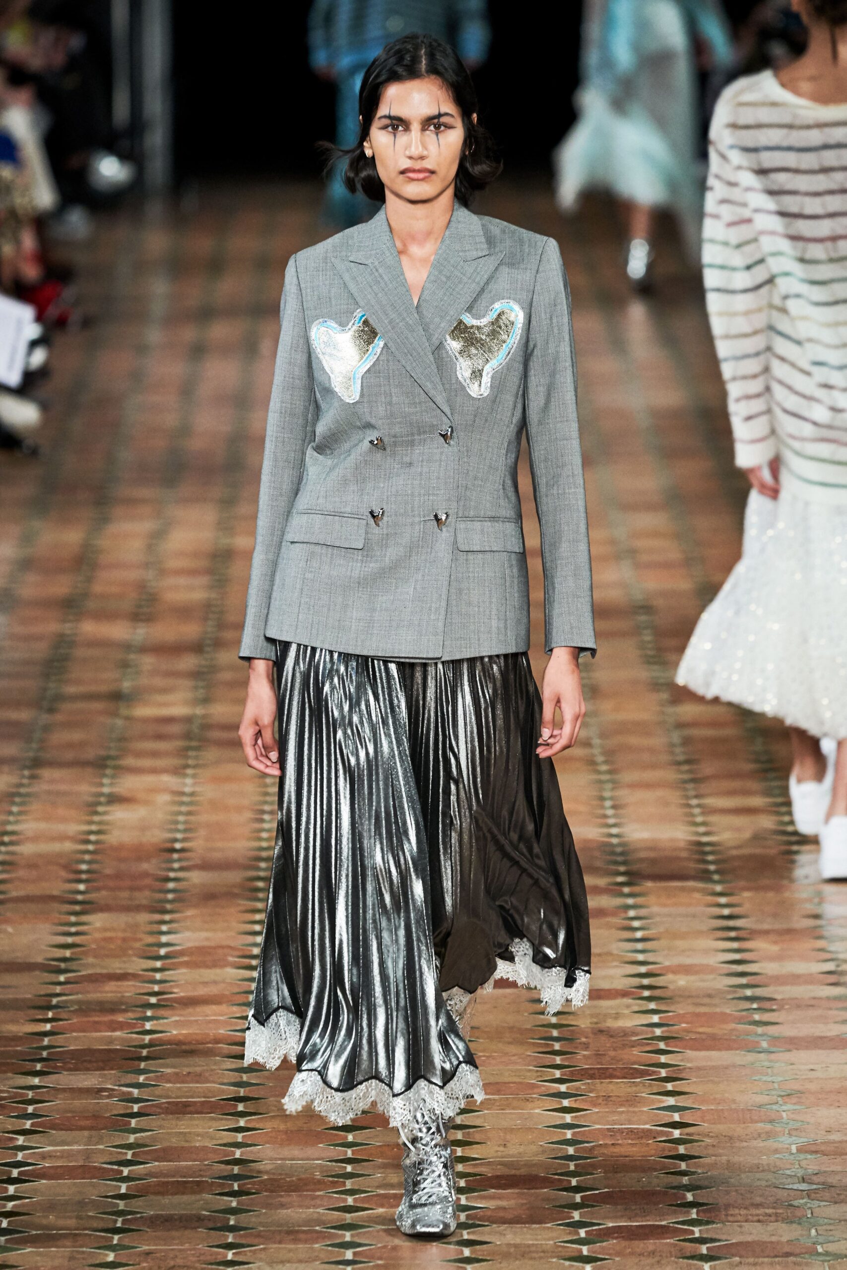 gray tailored blazer with embroidered details and black pleated skirt