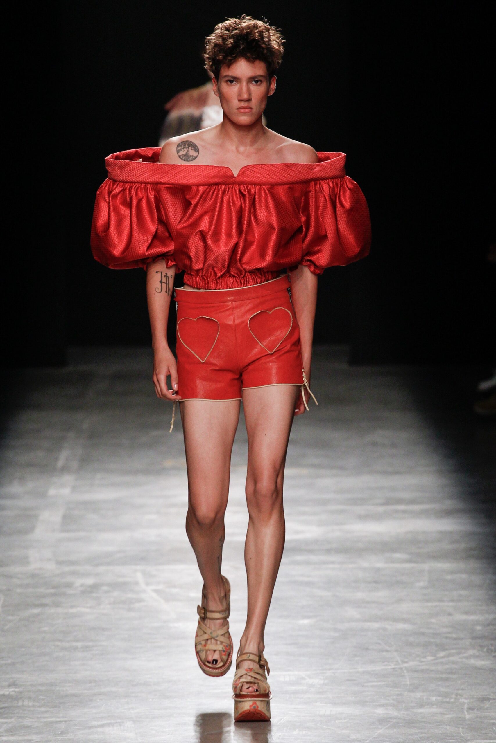 red silk off-shoulder top with leather shorts