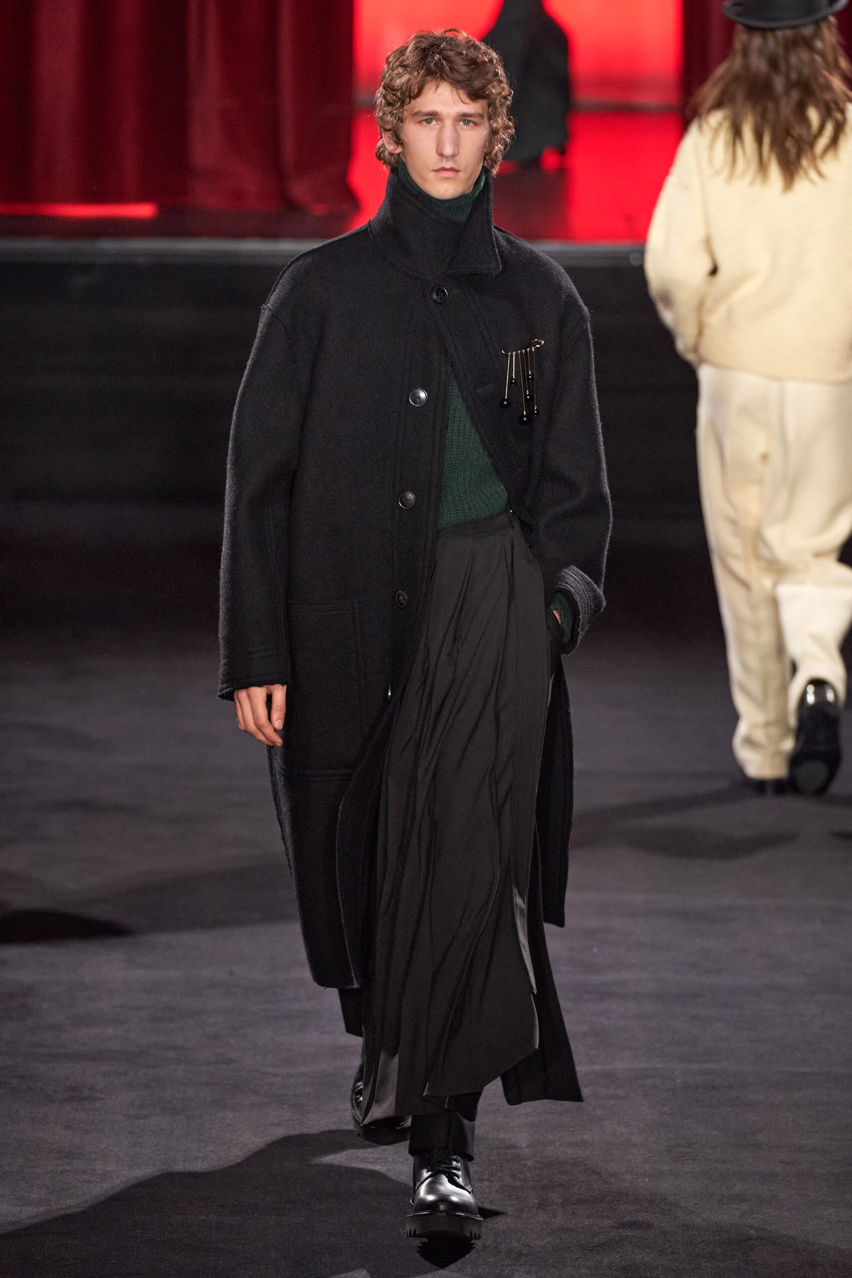 black wool coat green top pleated skirt