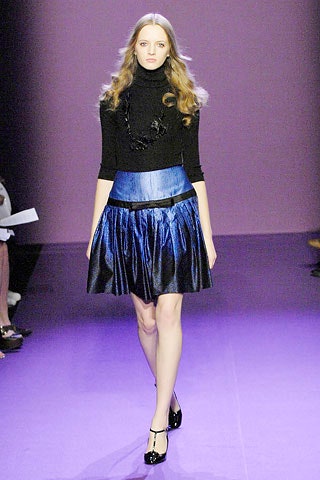 black fitted turtleneck top and blue pleated mini skirt