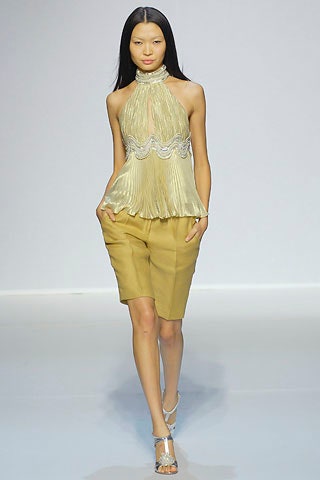 gold pleated sleeveless top with beige shorts