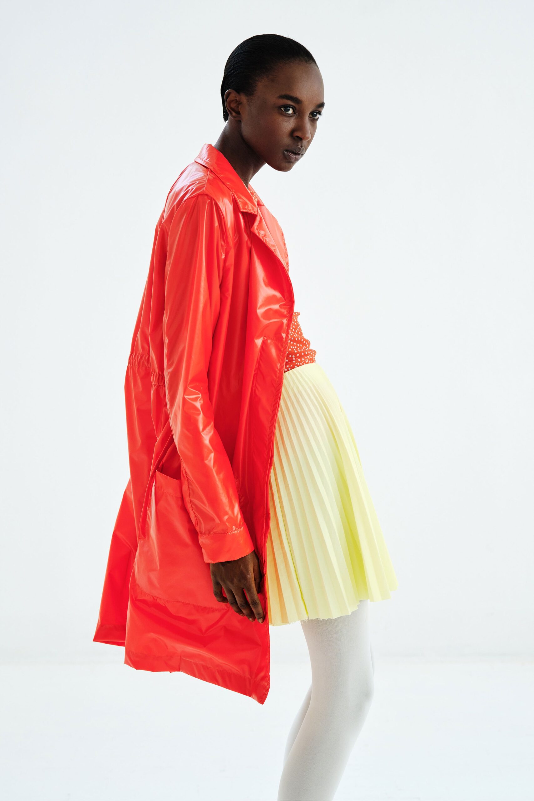 orange vinyl coat and yellow pleated skirt