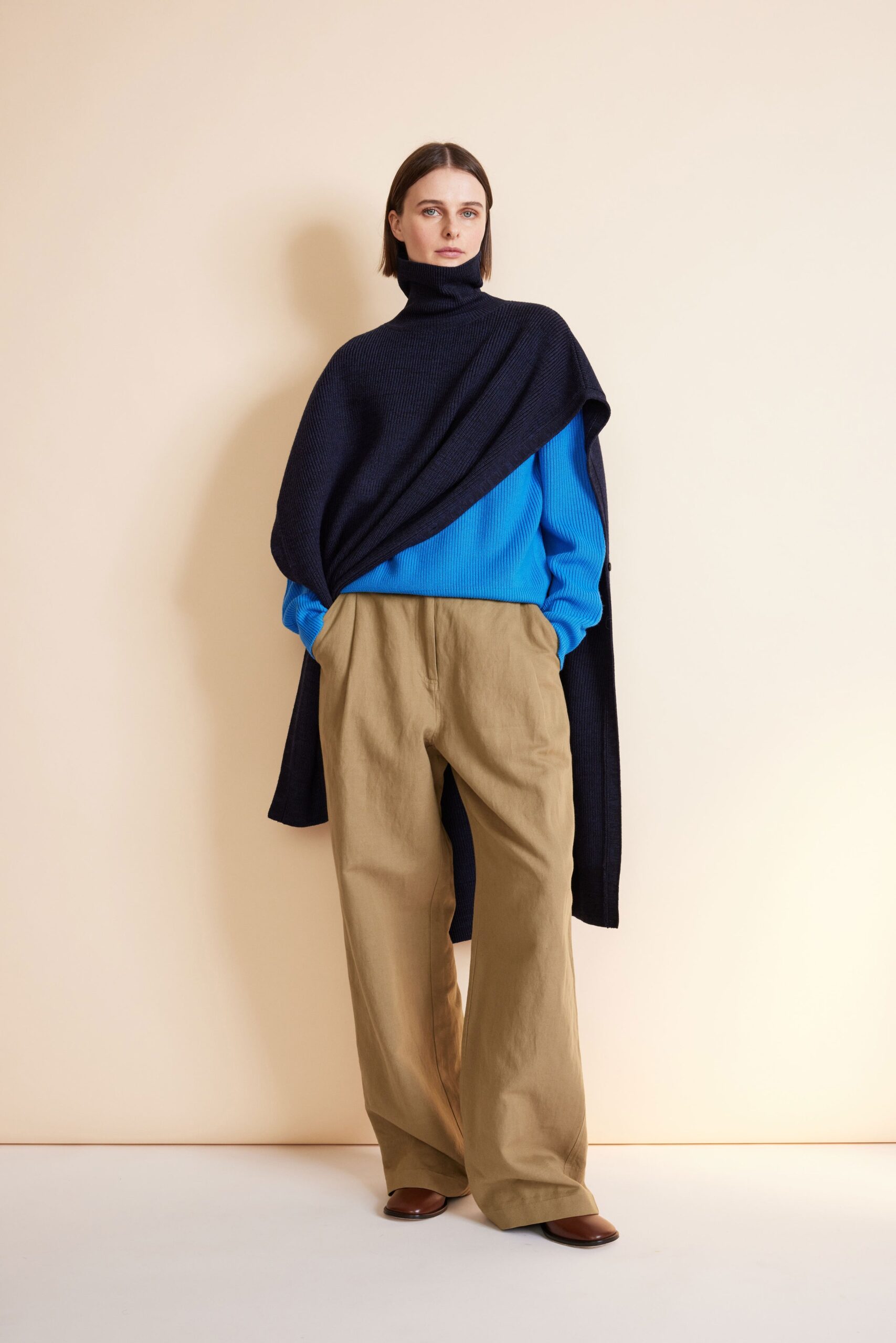 blue sweater black cape beige pants