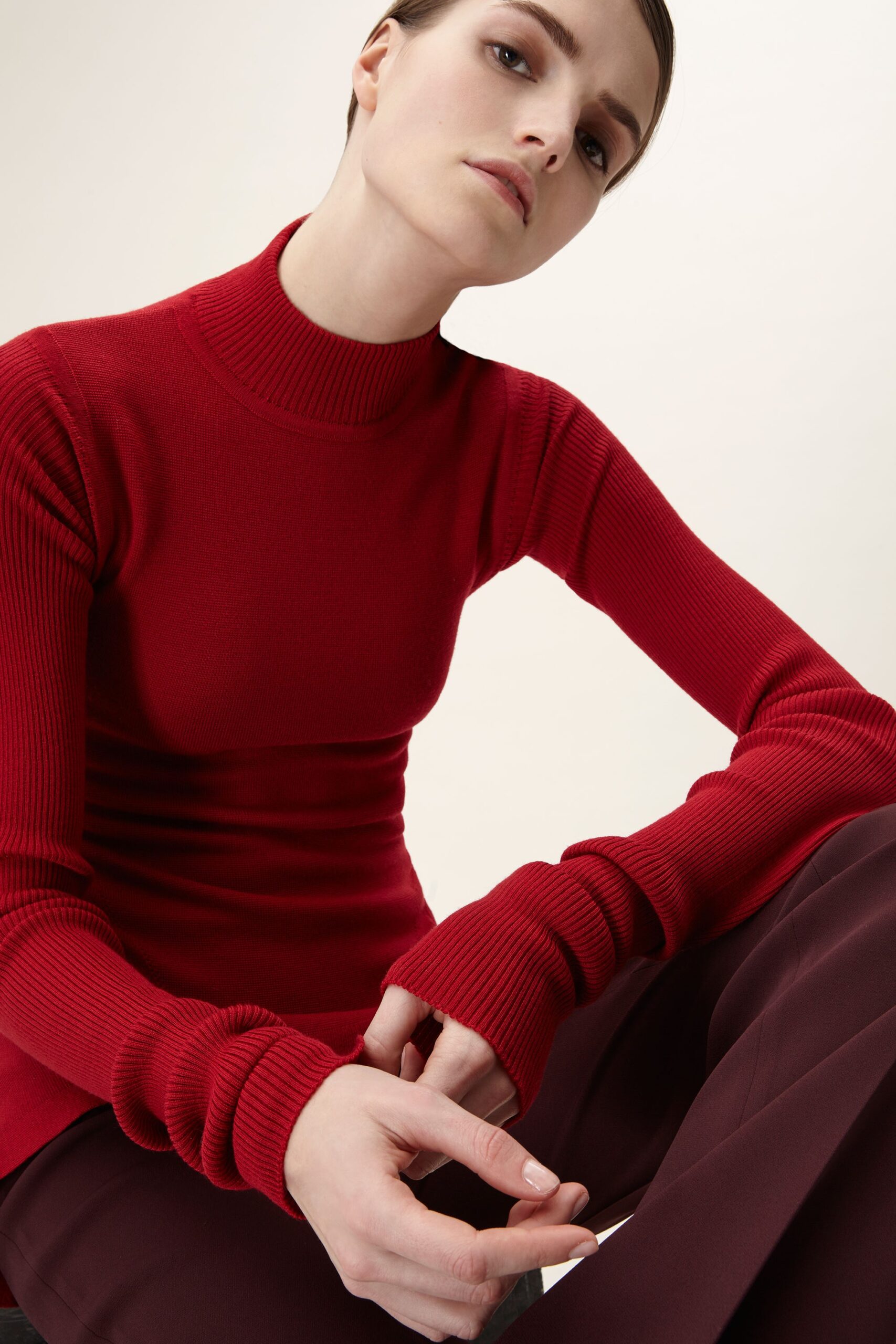 red fitted top with brown tailored pants