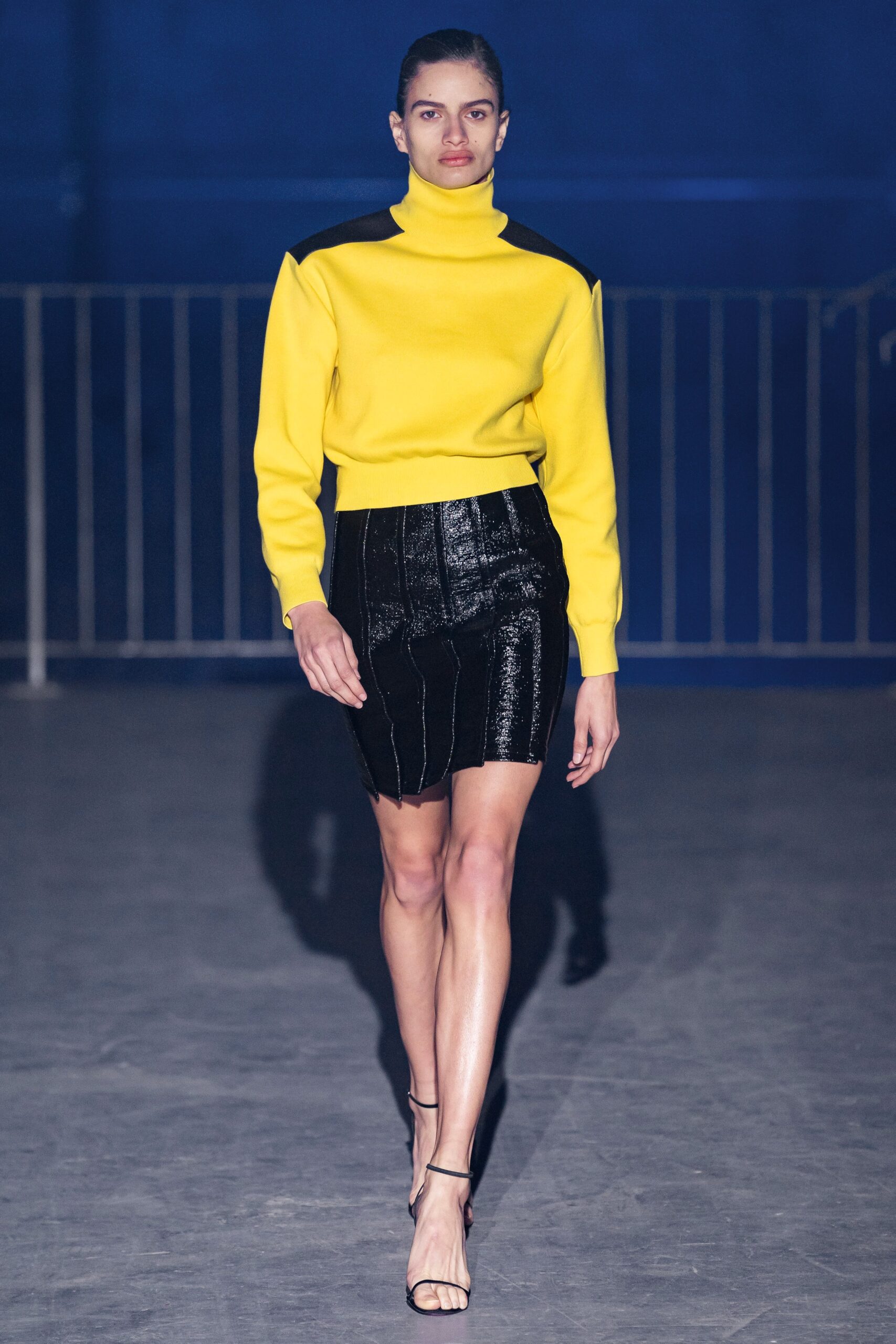 yellow fitted sweater and black vinyl skirt