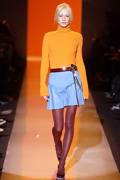 orange fitted turtleneck with blue pleated skirt