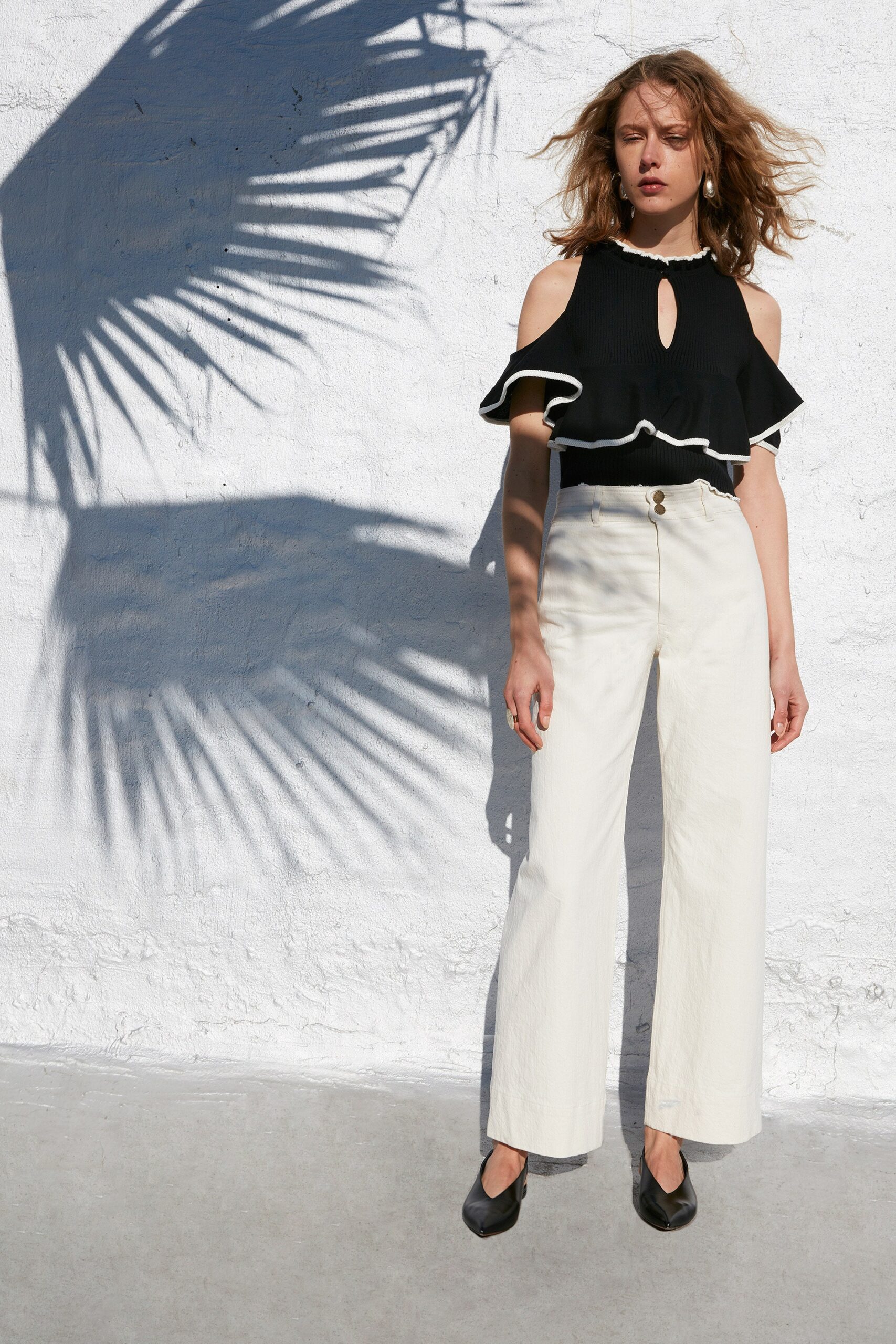 black ruffled top with white pants
