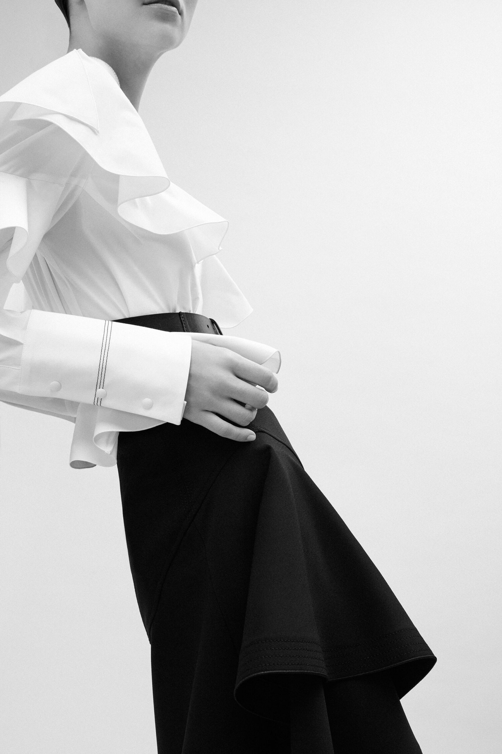 white ruffled blouse and black flared skirt