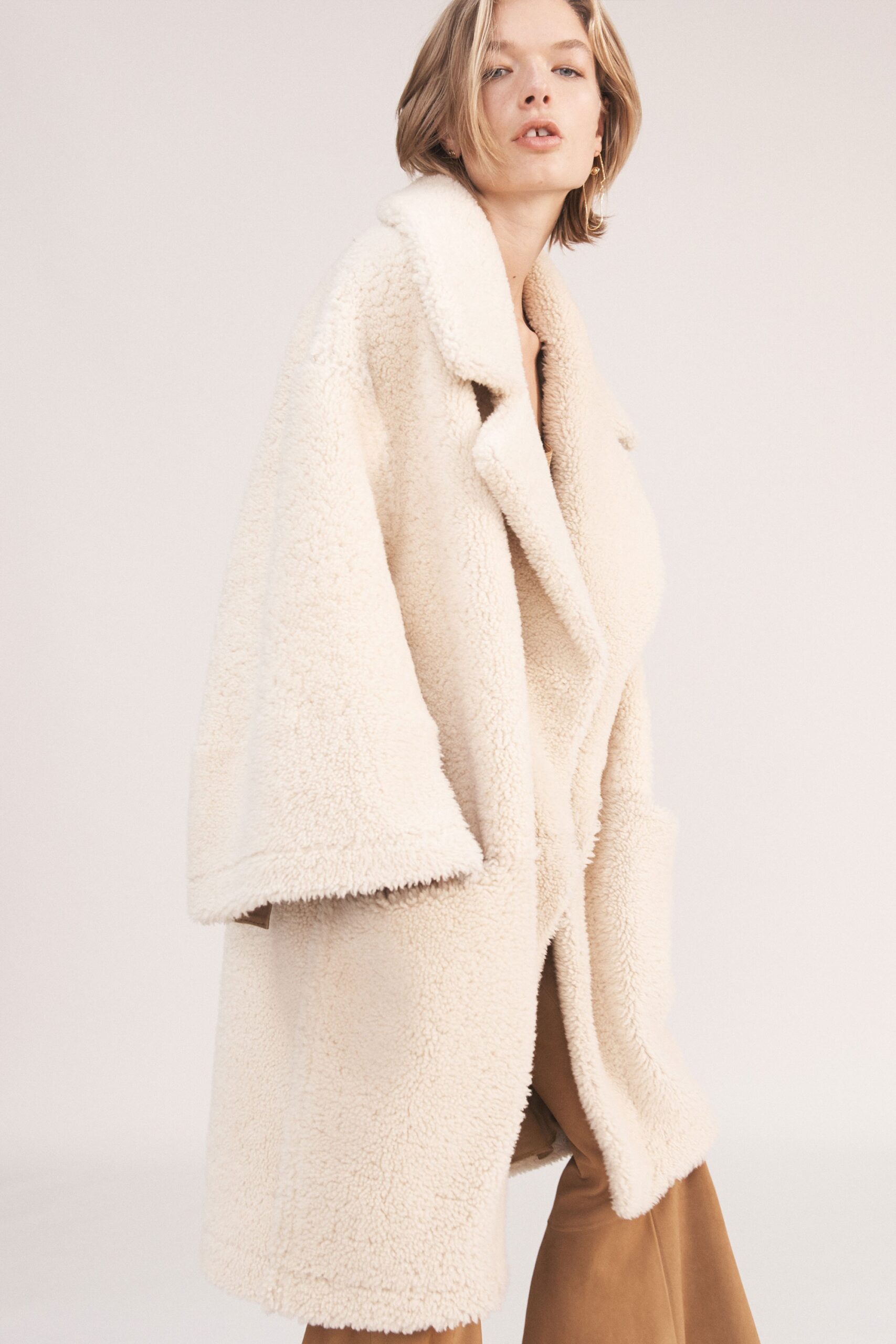 beige faux-fur oversized coat and brown tailored pants