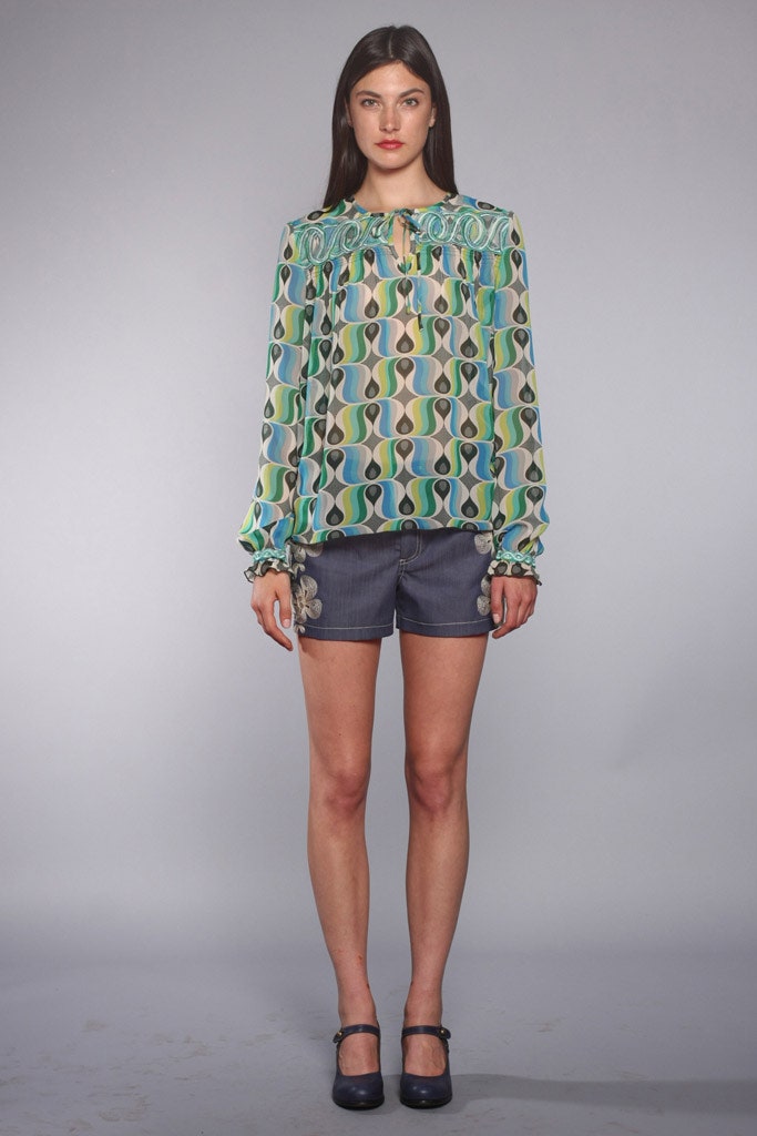 printed silk blouse and gray shorts