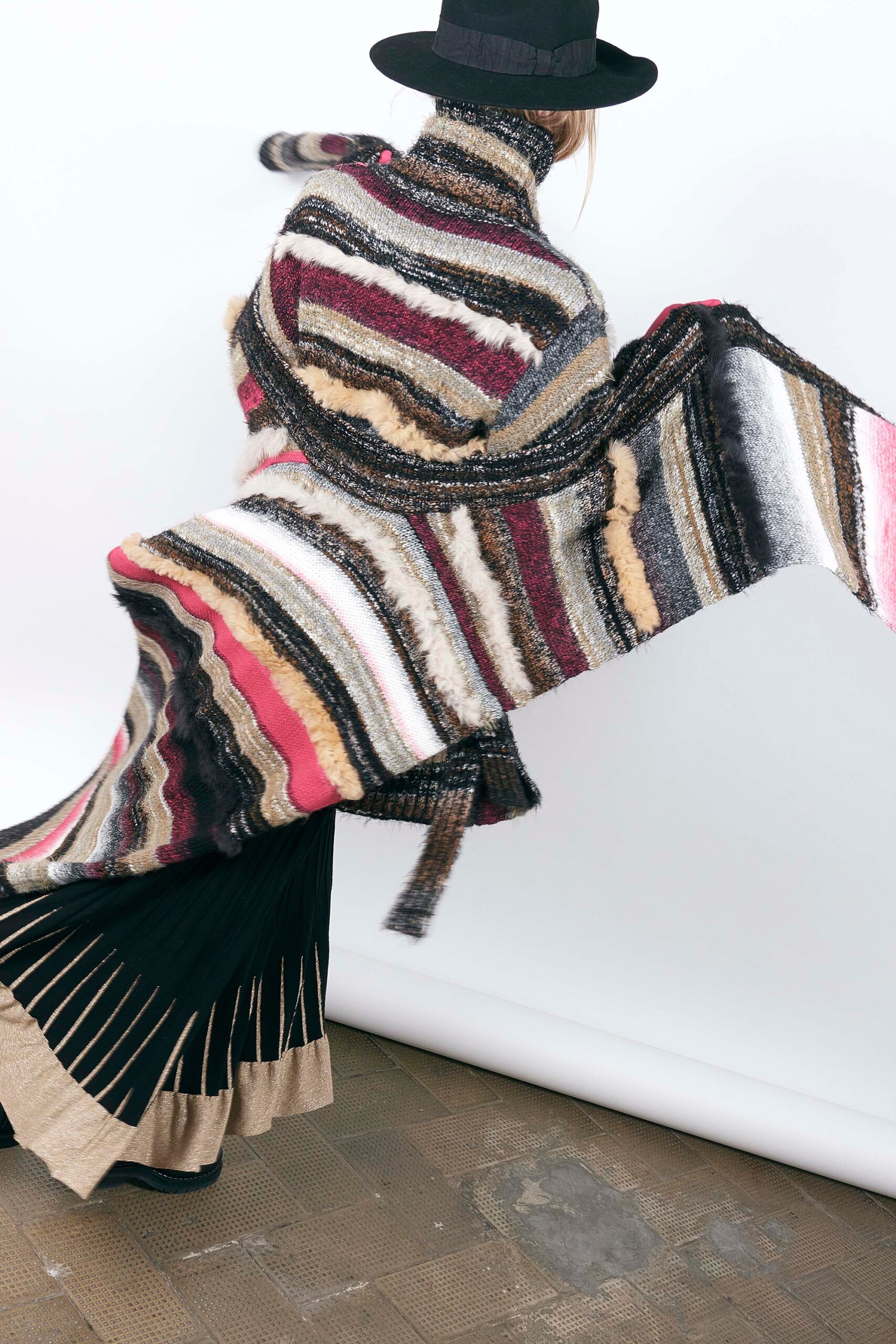 multi-colored wool cape and black pleated skirt